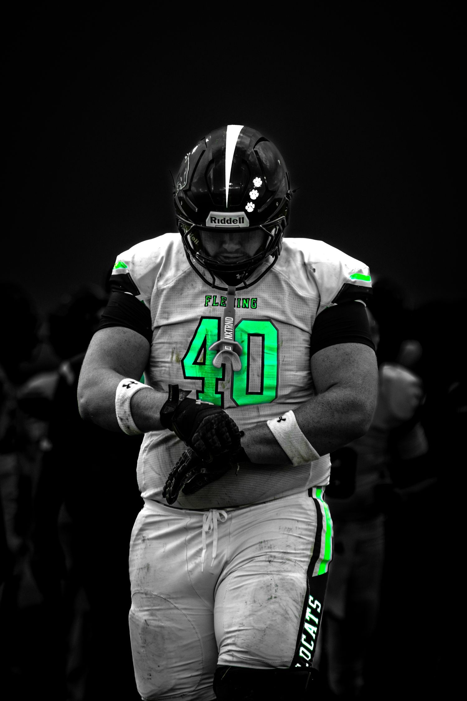A powerful Wildcats number 40 football player walks forward in a dramatic selective color edit.