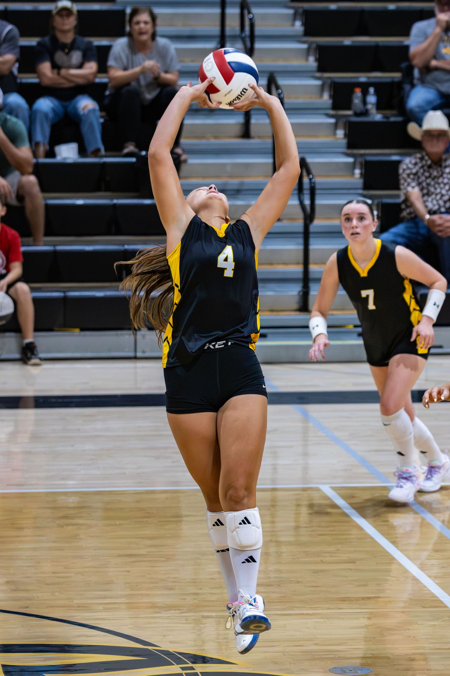 Caliche volleyball player number 4 sets the ball during a high school volleyball match.