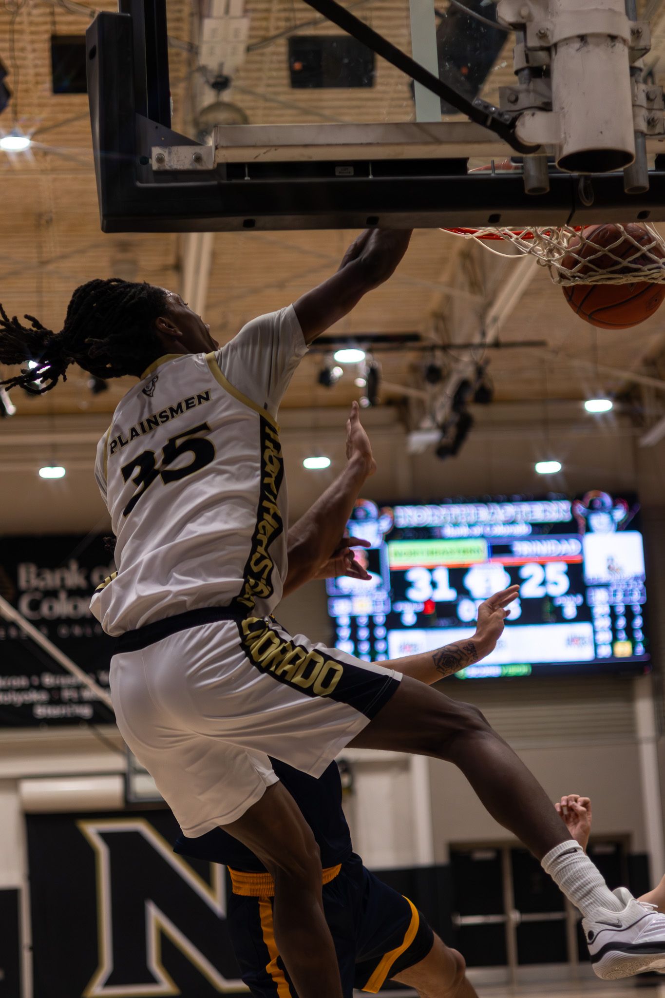 NJC Plainsmen player #35 dunks the ball during a college basketball game with score 31-25 on scoreboard.