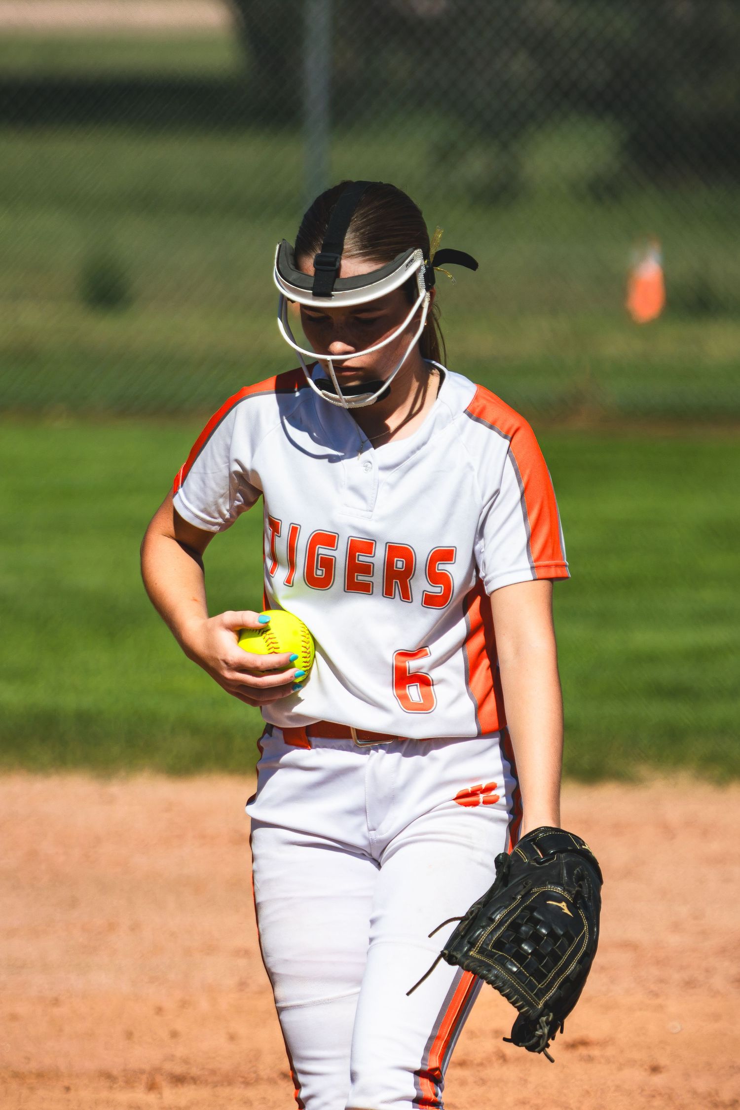 Softball pitcher number 6 in Tigers uniform holding yellow ball on the pitching mound.