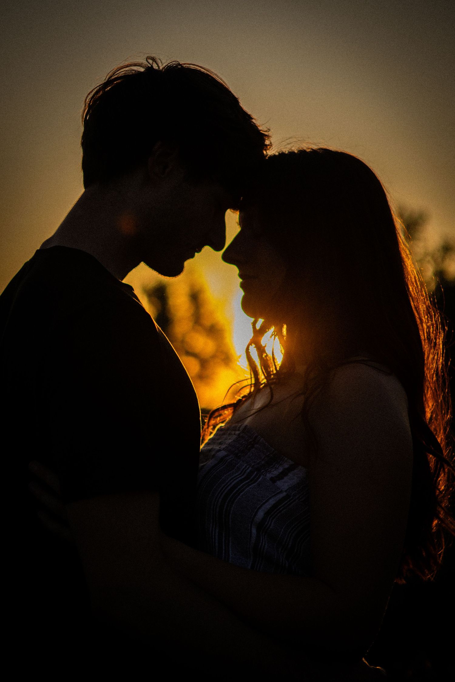 Romantic silhouette of a couple facing each other at golden sunset.