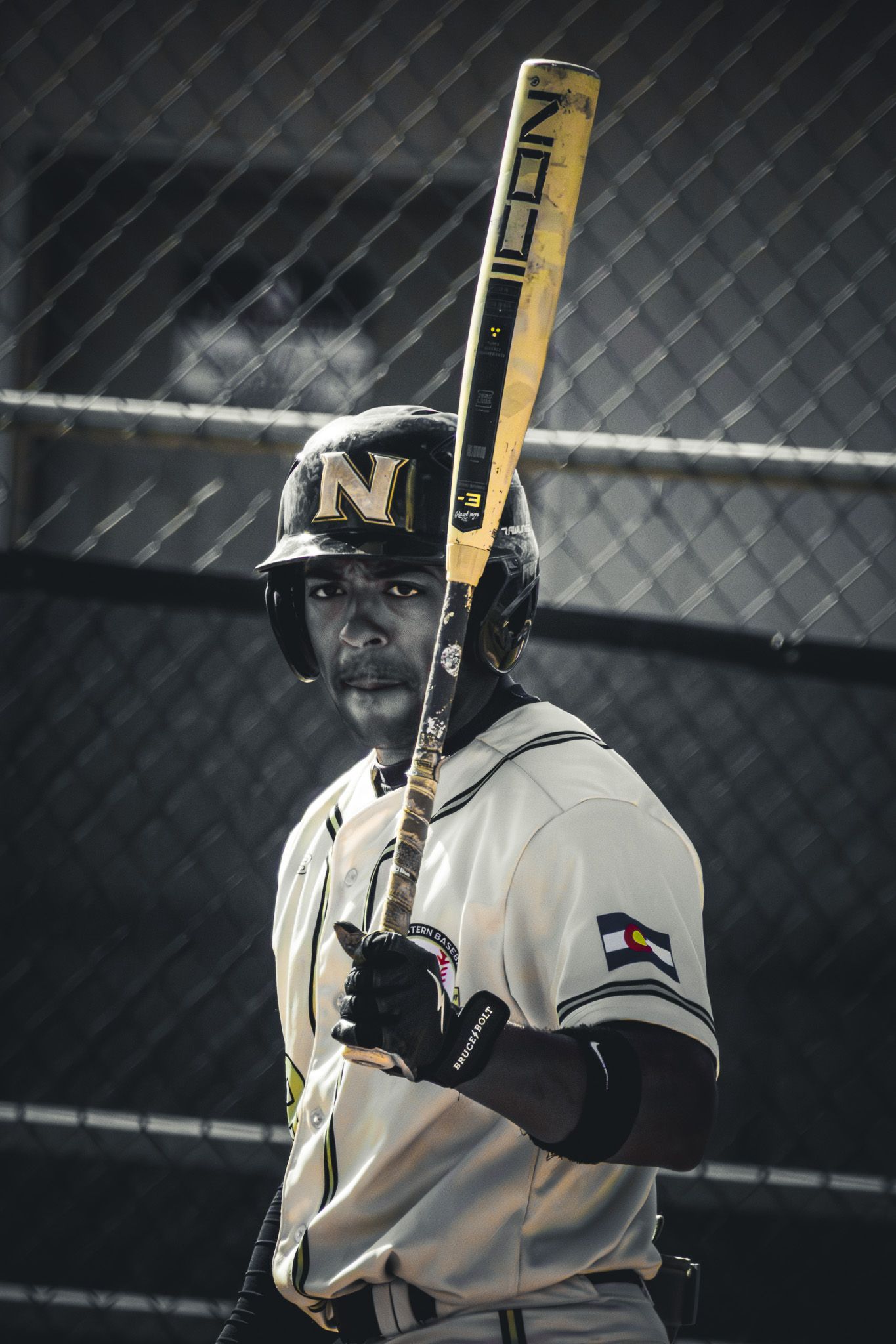 Baseball player in uniform holds bat ready to bat in dramatic portrait shot.