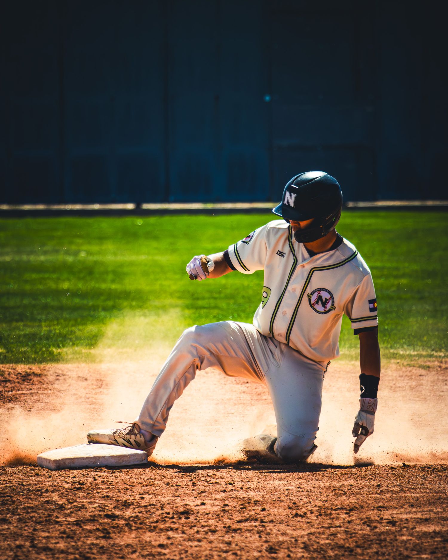 A baseball player slides into base creating a cloud of dust during an action-packed game.