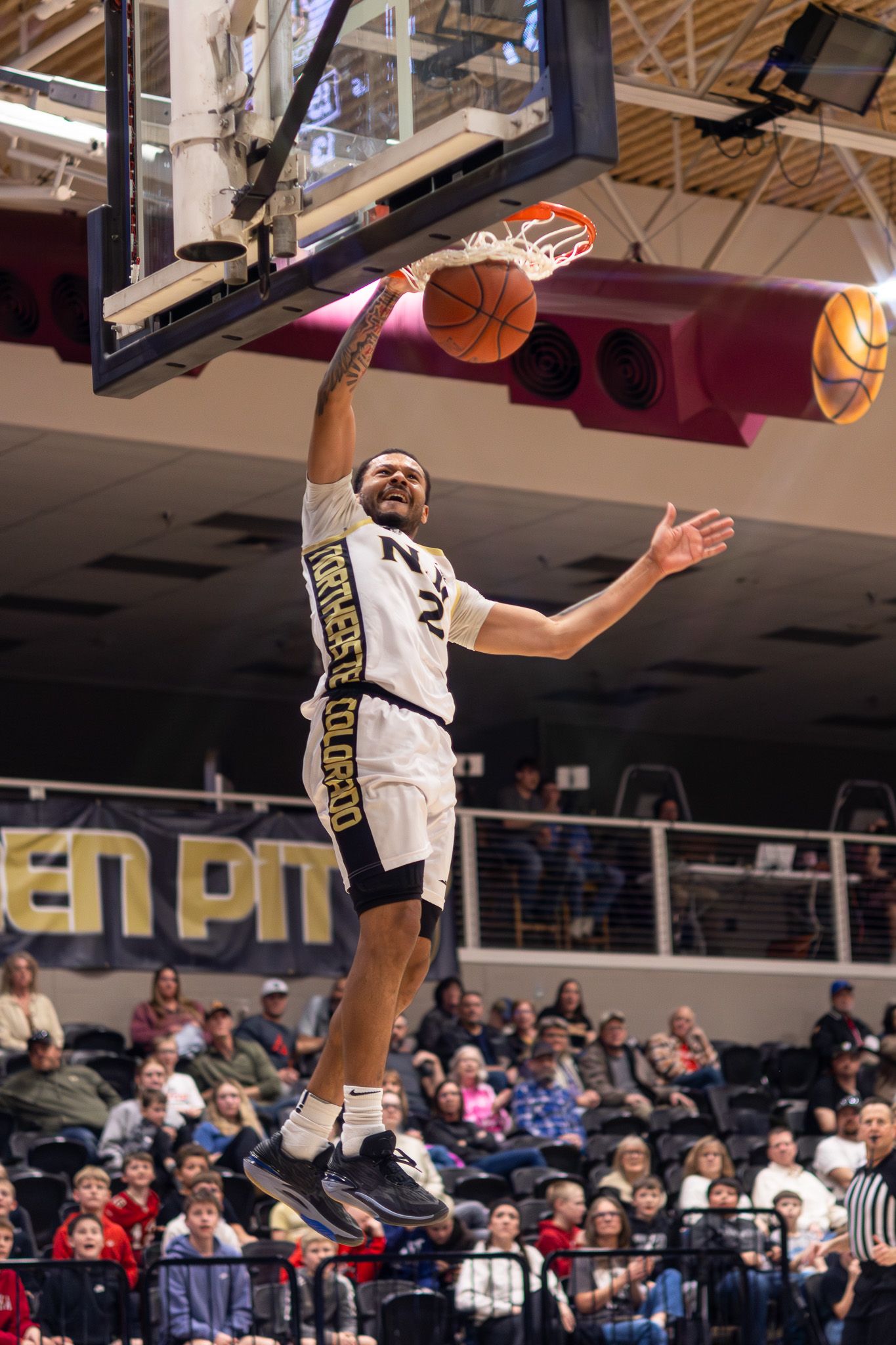 NJC Plainsmen player throws down a powerful dunk in front of a packed college basketball arena crowd.