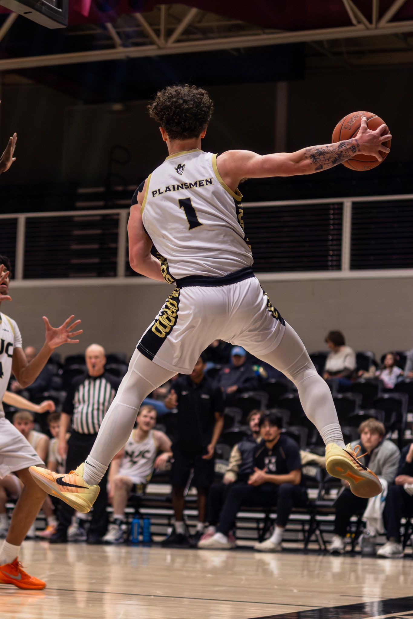 Plainsmen player number 1 leaps to save the ball from going out of bounds during a basketball game.