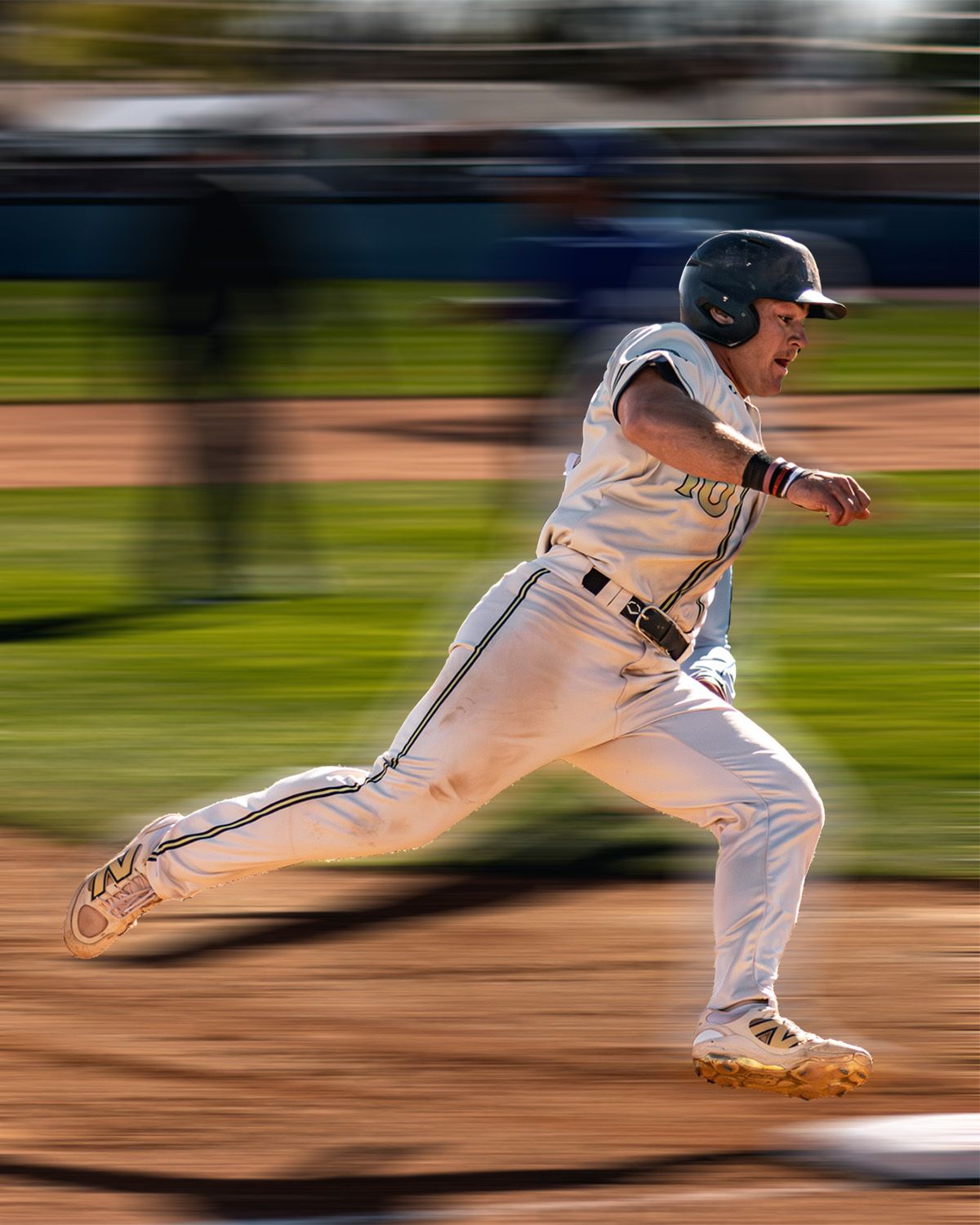 Baseball player sprints bases in motion-blurred action shot.