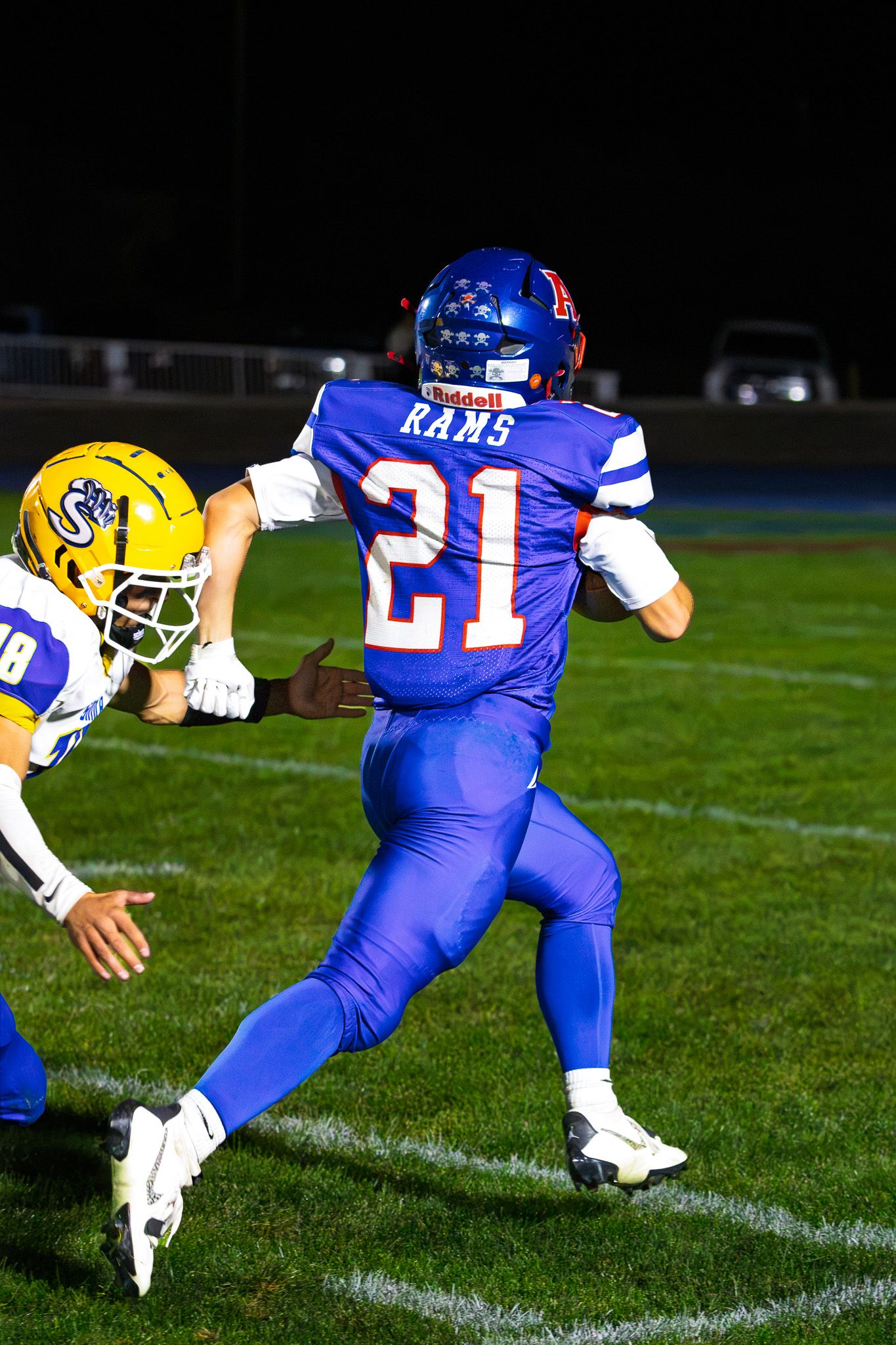 Rams football player number 21 in blue uniform runs with ball during night game action.