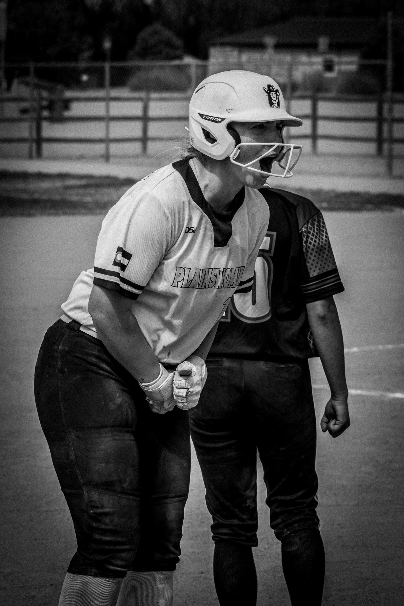 Black and white photo of two softball players facing off near base during game.