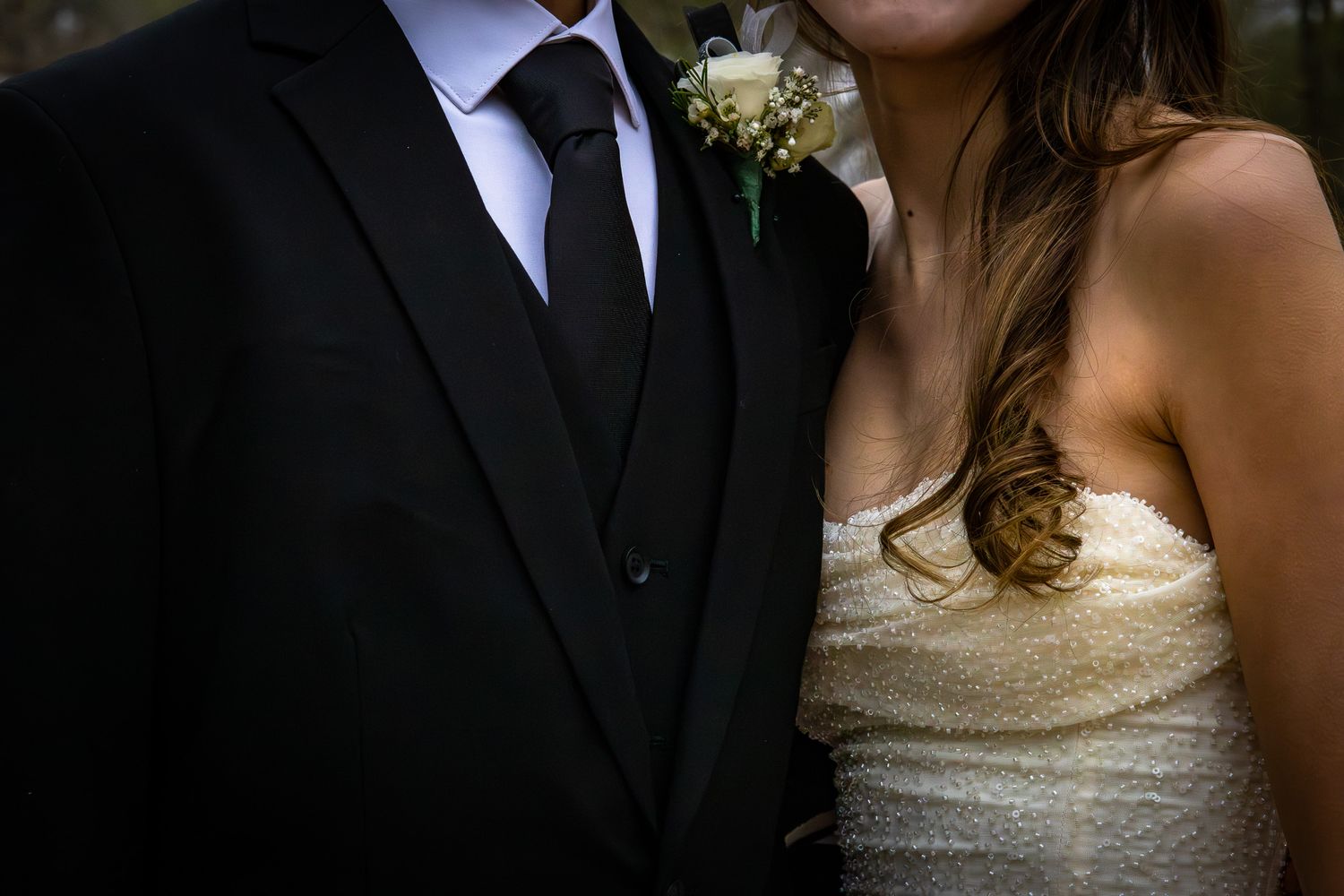 Close-up of a bride and groom in wedding attire, groom wearing a boutonniere.