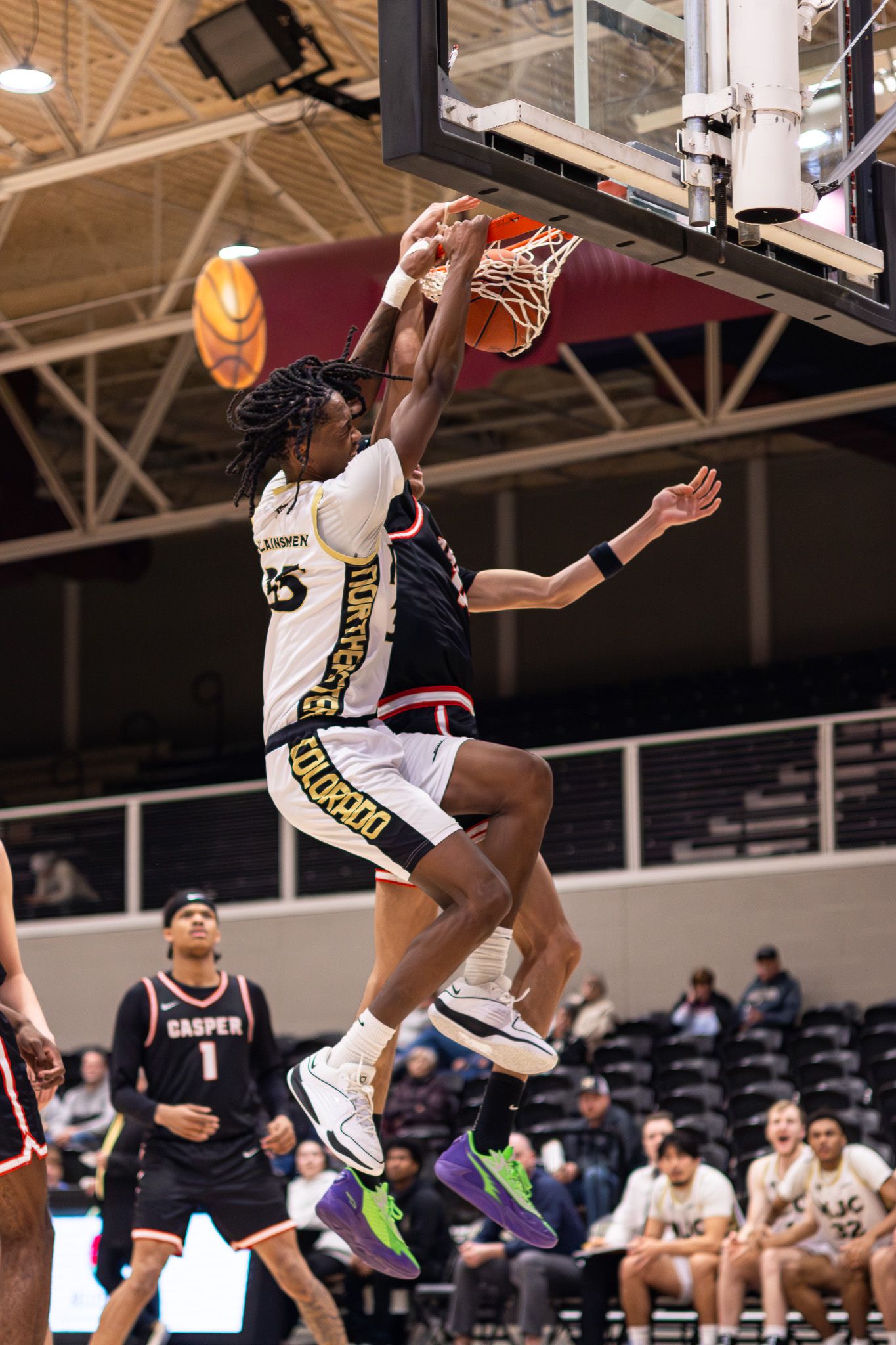 NJC Plainsmen player #35 dunks over a Casper College defender in a college basketball game.