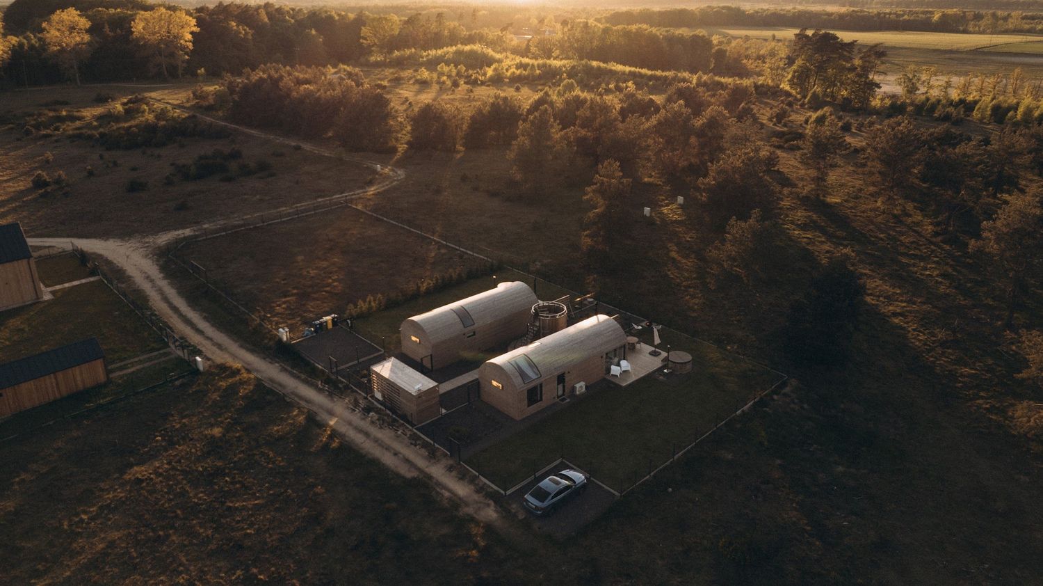 Aerial view of a rural farm property with white buildings surrounded by golden fields at sunset.