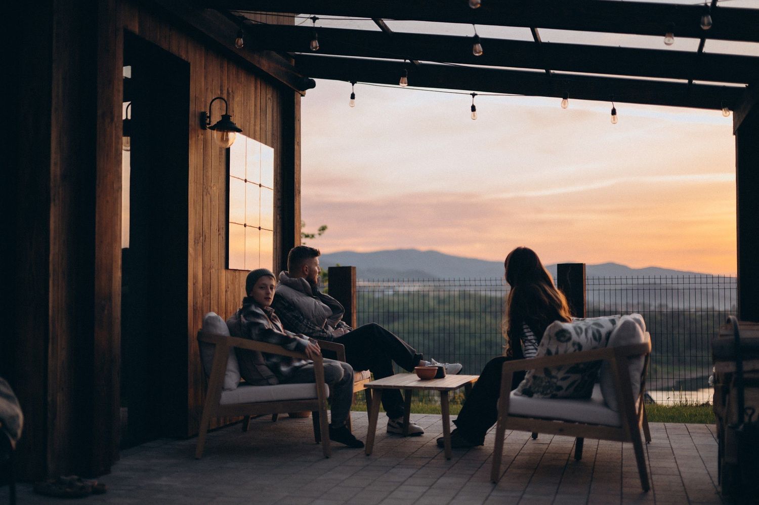 Group of friends relaxing on a covered porch with stunning mountain sunset views.