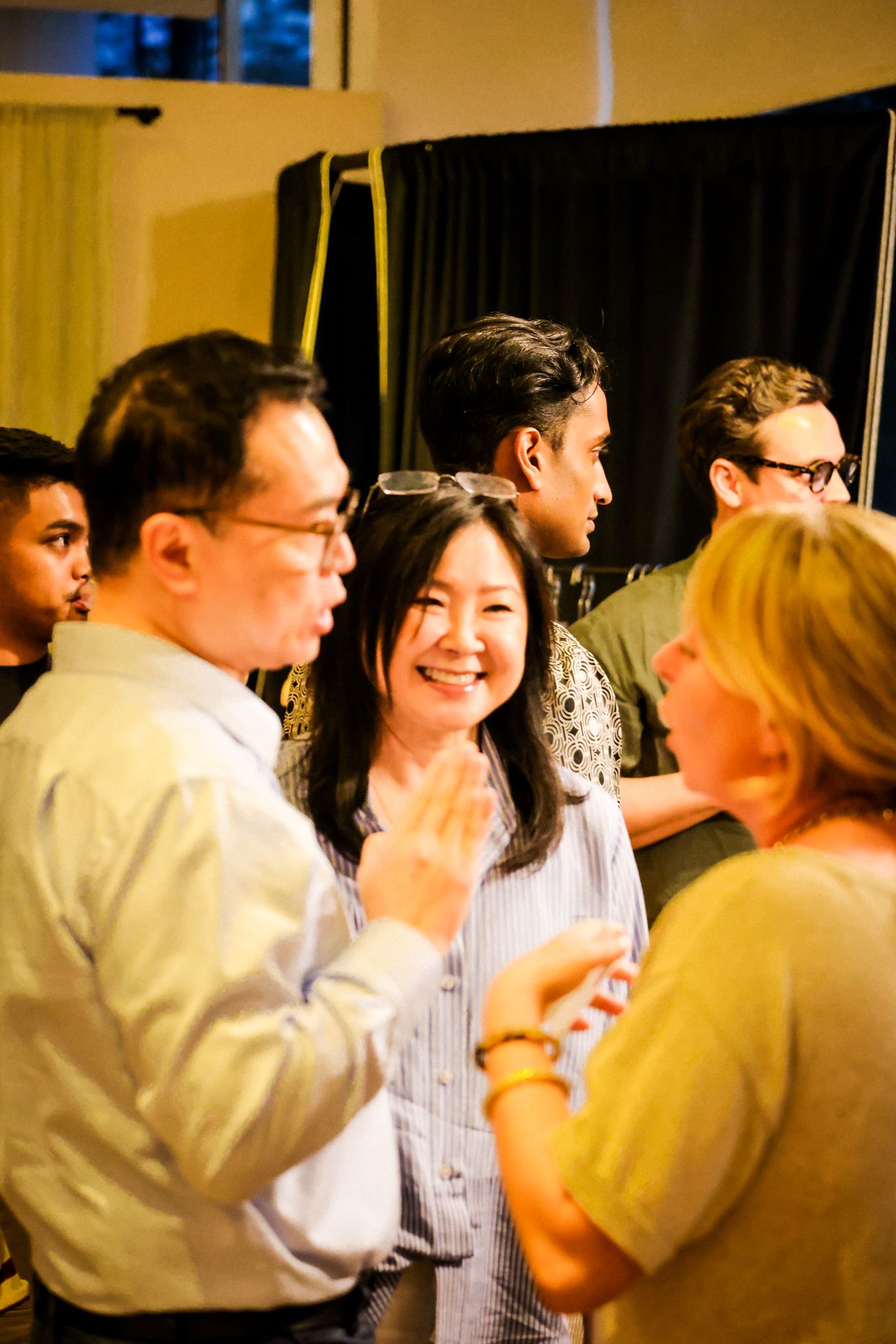 A diverse group of people socializing and conversing at an indoor networking event or party.