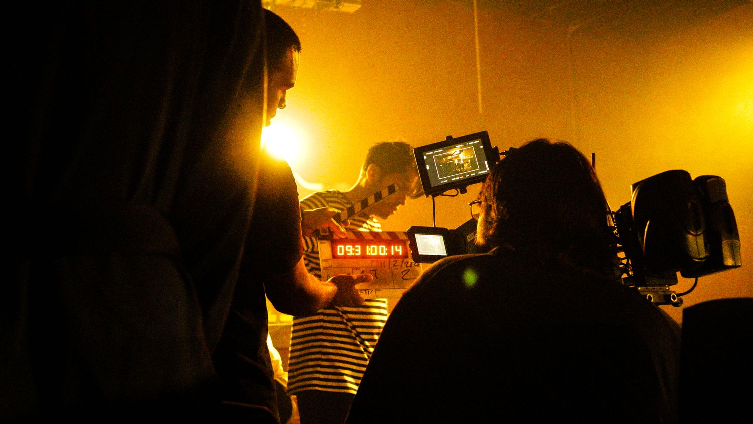Behind-the-scenes film production in a bar with camera monitor displaying the shot in warm light.