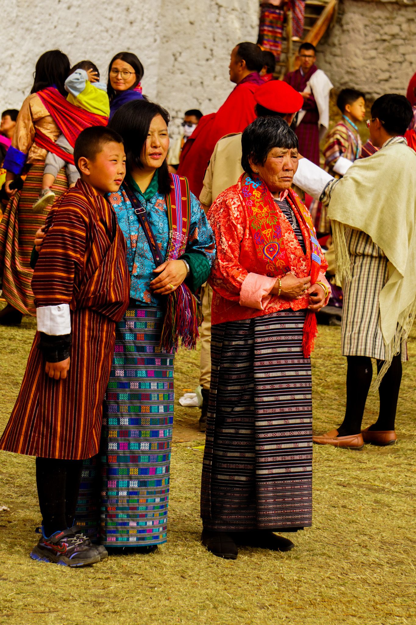 Bhutanese family in traditional gho and kira attire stands together at outdoor cultural festival.
