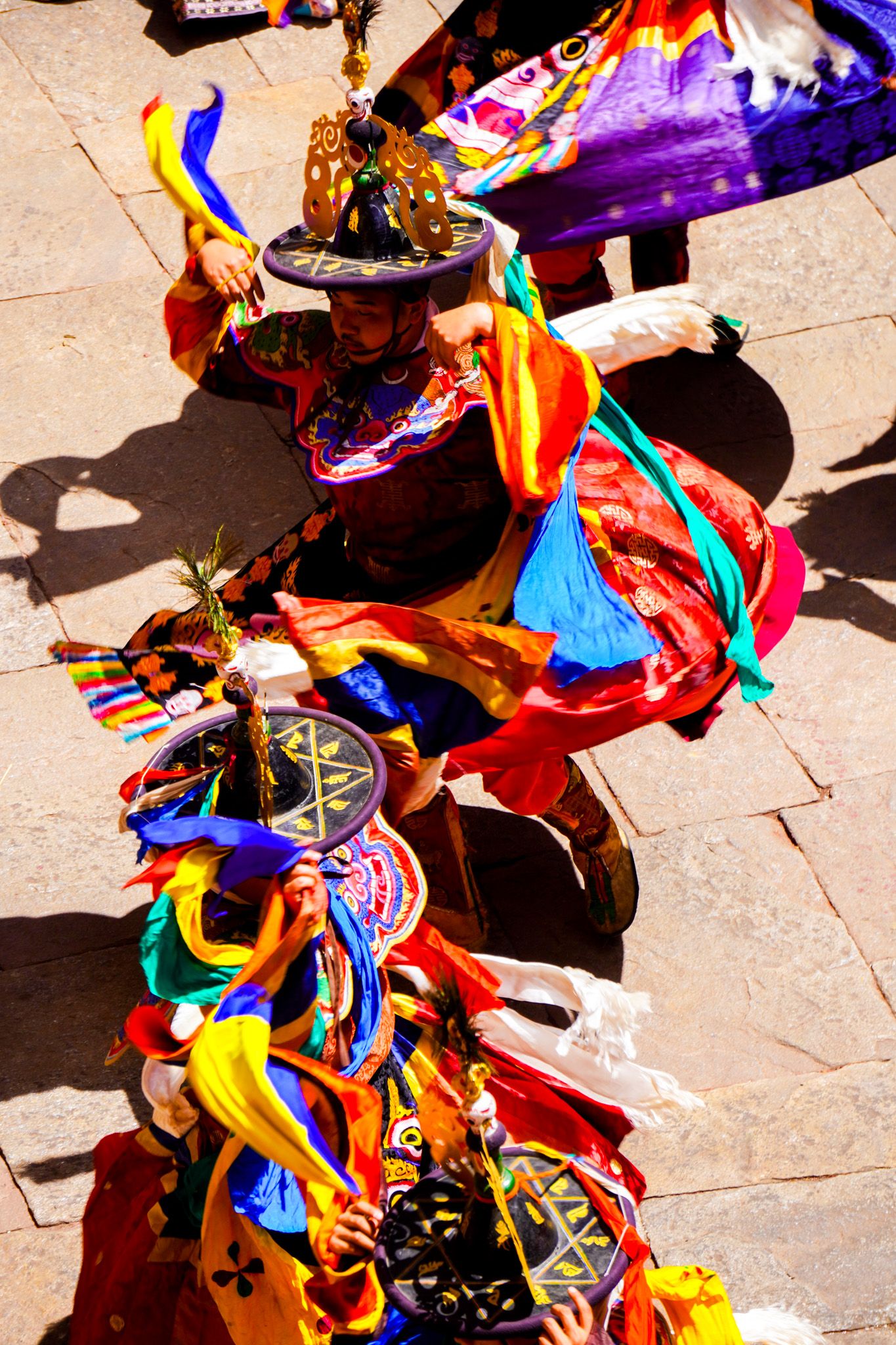 Elaborately costumed Bhutanese Cham dancers perform with colorful ribbons at a Tsechu festival.