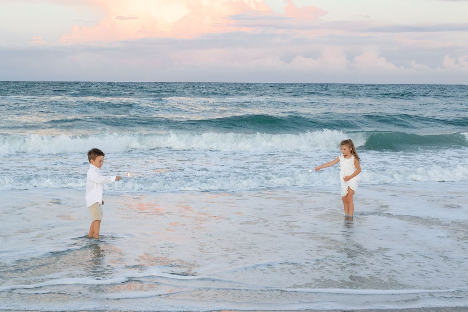Children at the waters edge at the beach with a beautiful pink sunset on Amelia Island, Florida