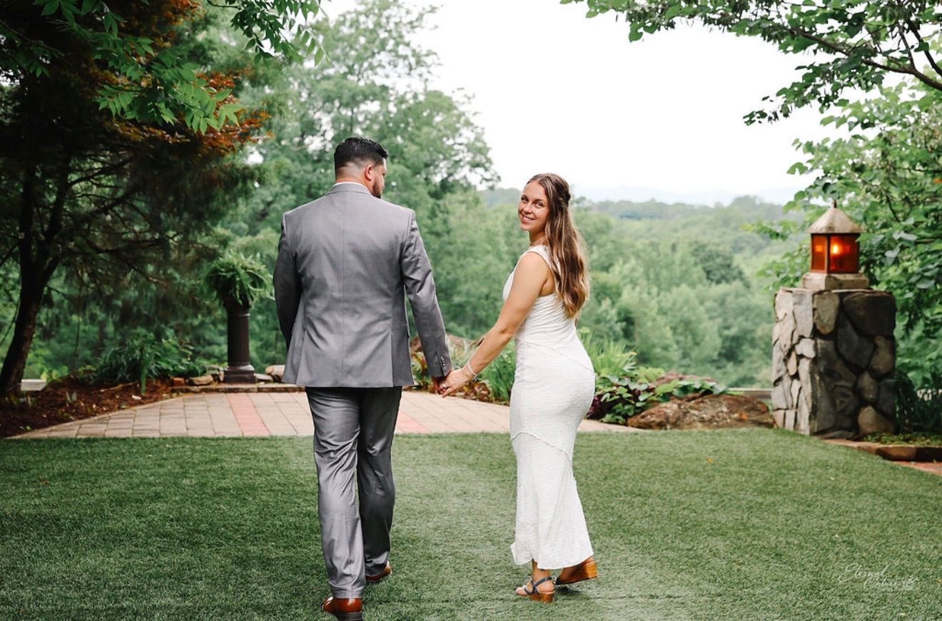 Bride and groom walking hand in hand through a lush garden venue after their wedding.