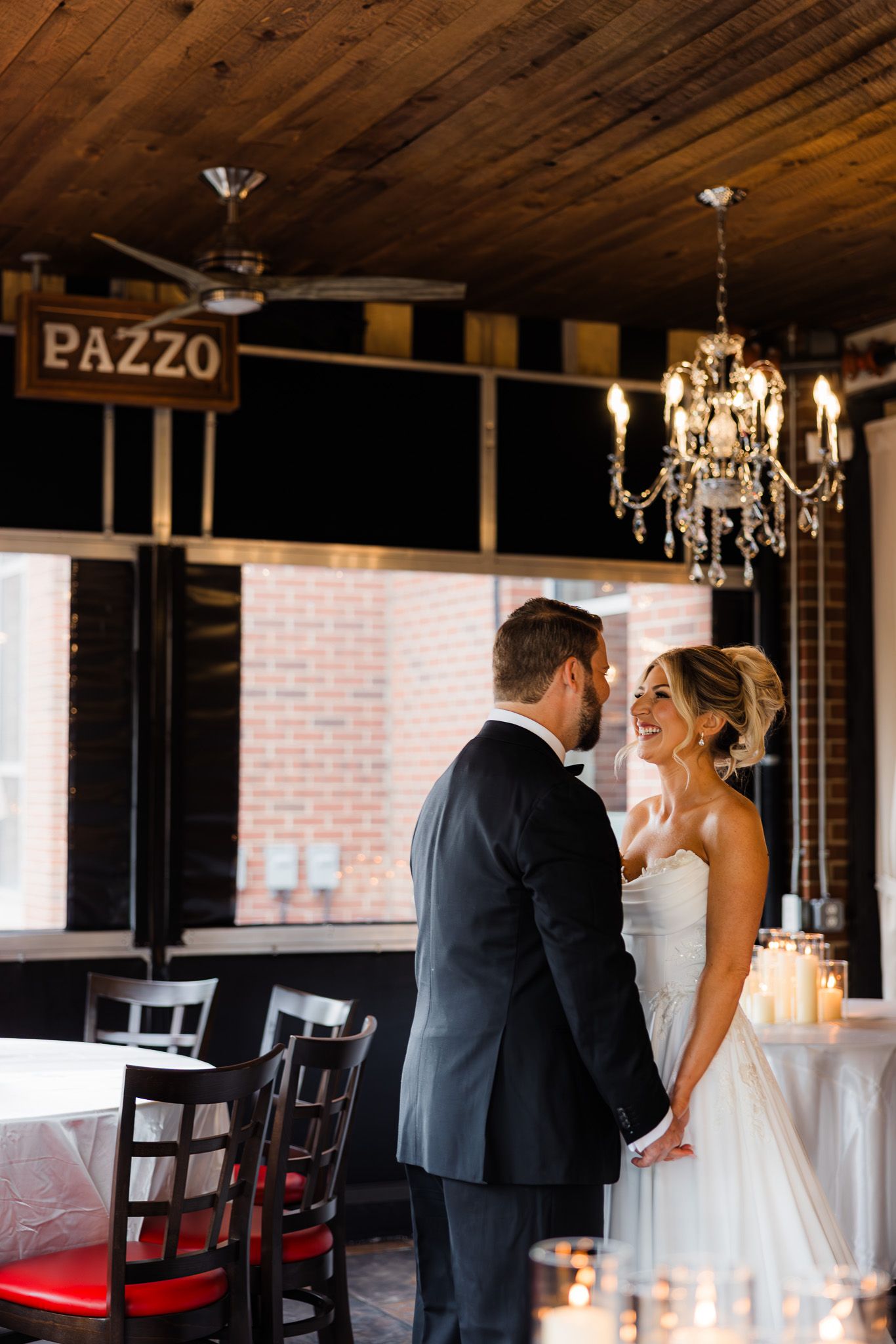 Bride and groom share a romantic moment under a chandelier at Pazzo restaurant wedding venue.