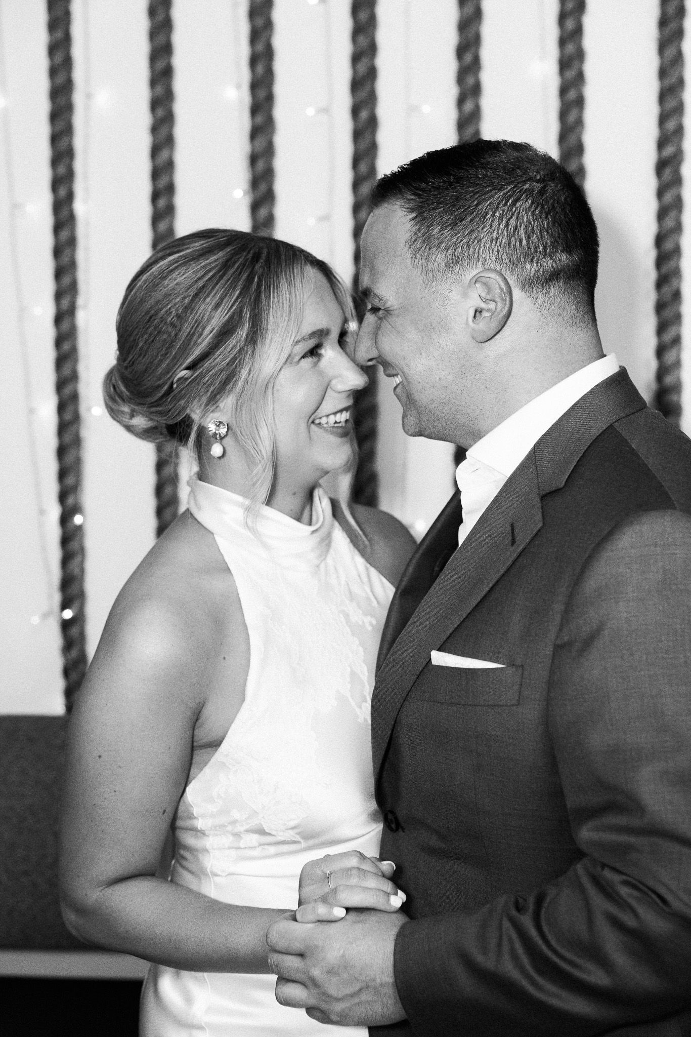 Black and white photo of a smiling bride and groom sharing a first dance at their wedding reception.