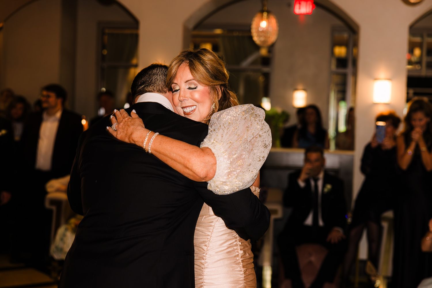Bride sharing emotional hug with guest during wedding reception dance on the dance floor.