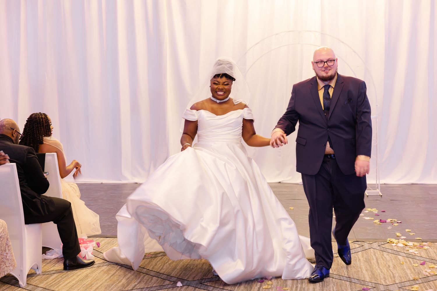 Bride in white ball gown walks with suited man at wedding reception ceremony.