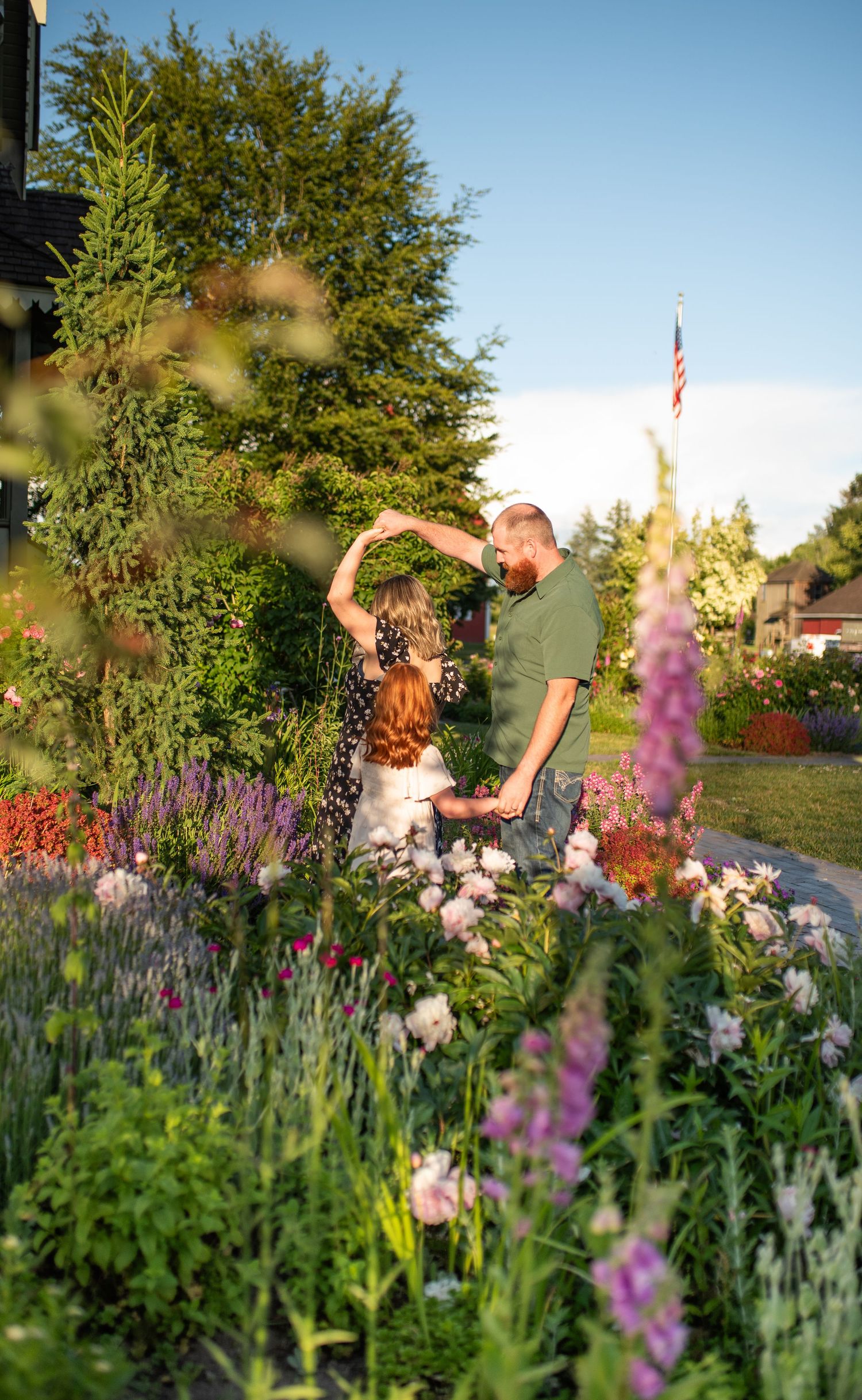 Couple dancing joyfully in a vibrant flower garden at golden hour.