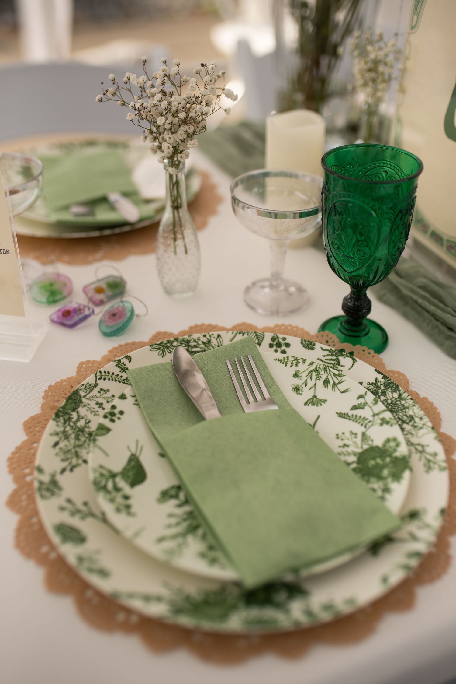 Green botanical wedding place setting with floral plate, green goblet, and baby's breath centerpiece.