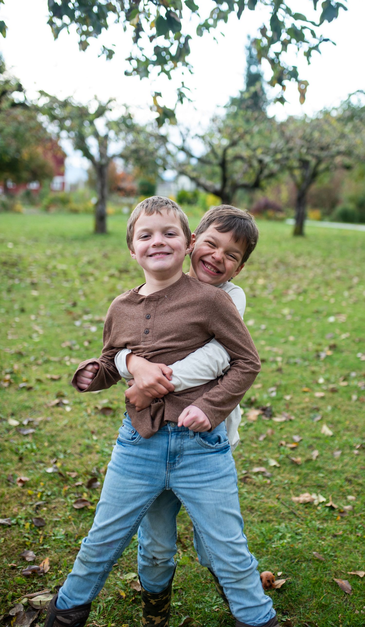 Two young boys laugh and play together in an autumn park.