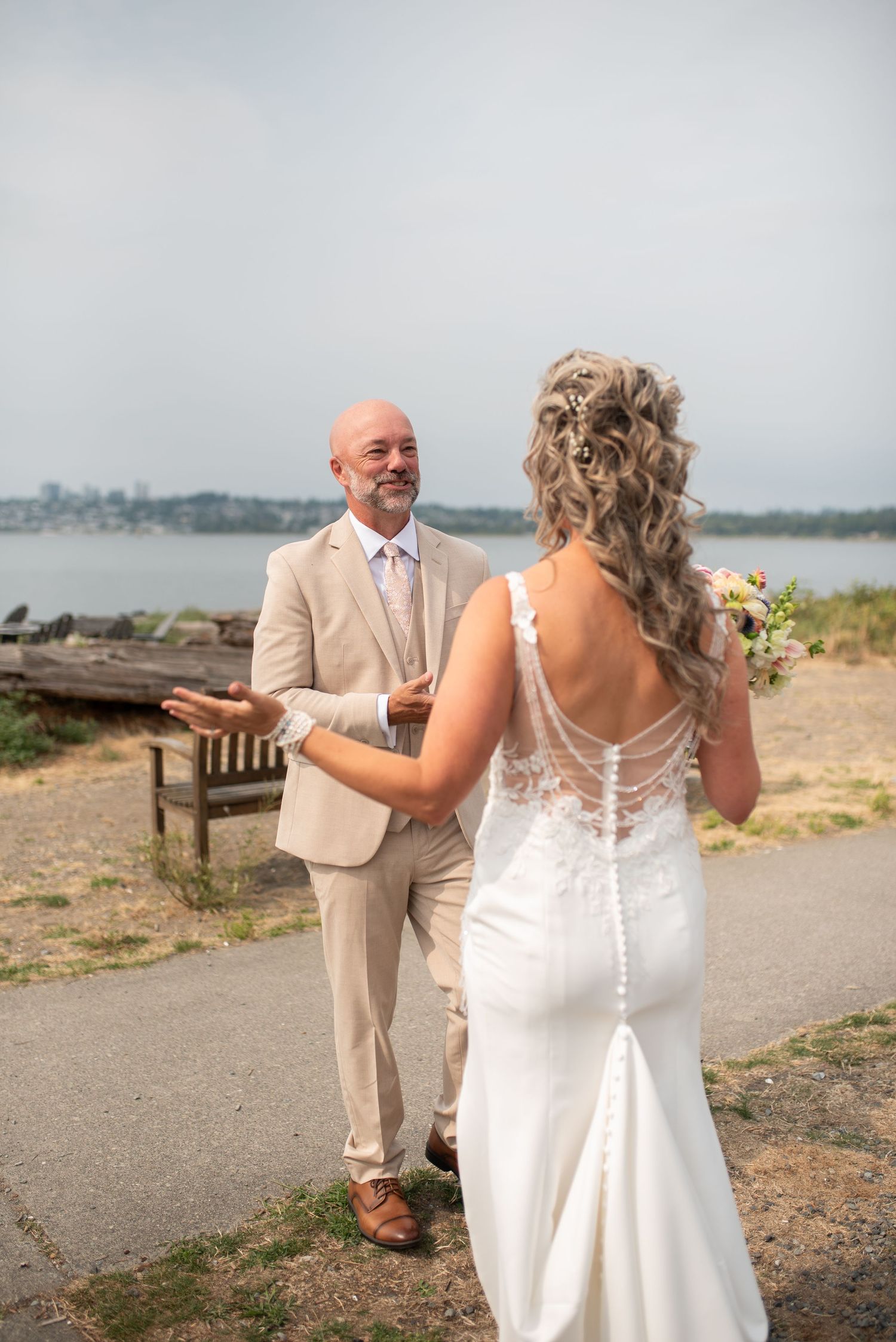 Groom reacts with joy and open arms seeing his bride for the first time during their waterfront first look.
