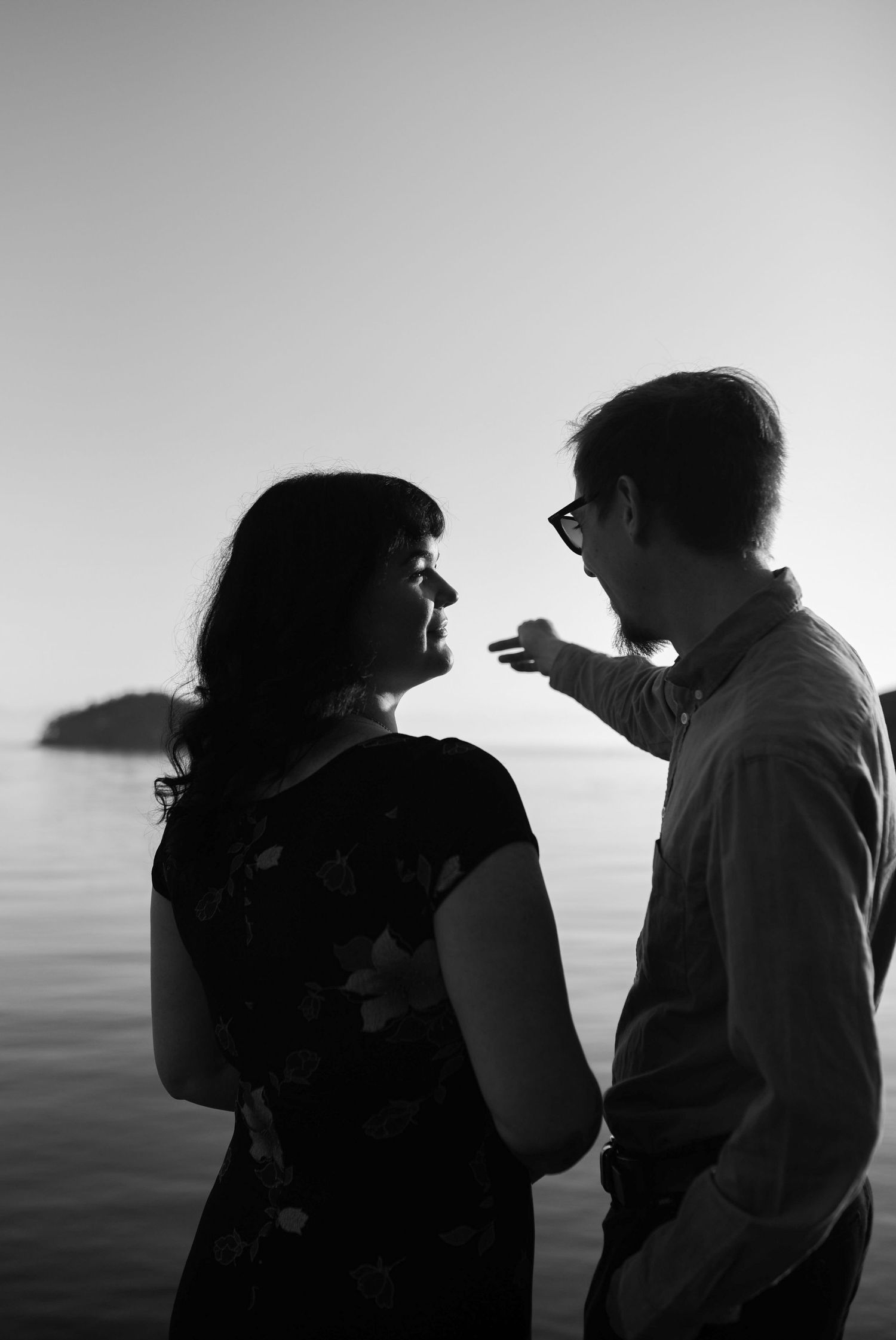 Black and white silhouette of couple sharing a tender moment by the ocean at dusk.