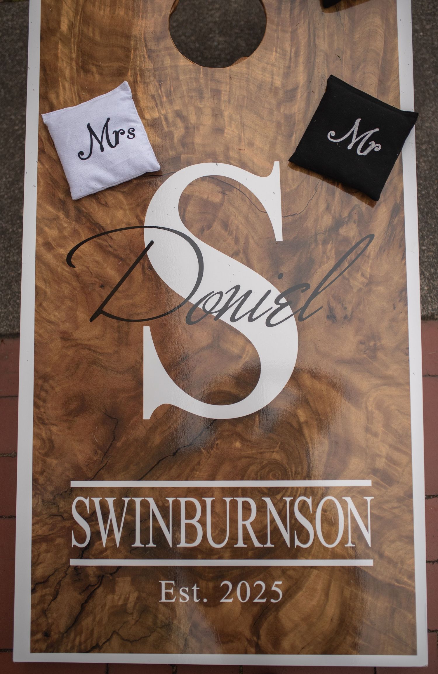 Custom wooden cornhole board for the Swinburnson family, Est. 2025, with Mr and Mrs bean bags for a wedding.