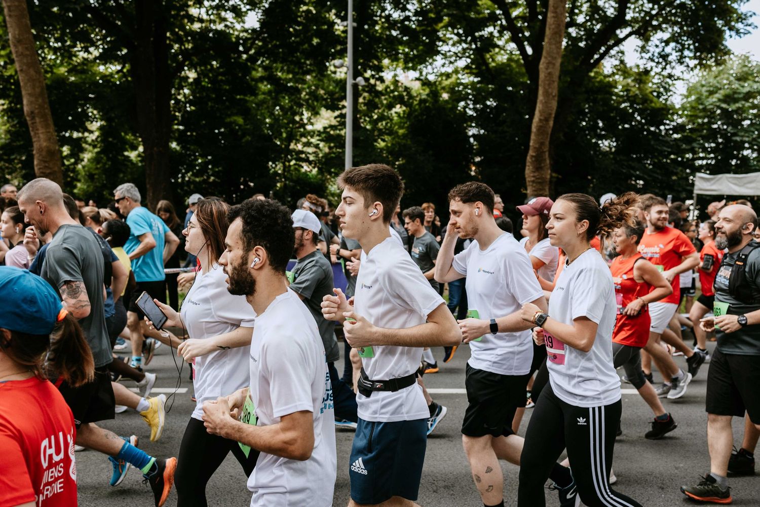 Group of runners in white shirts competing in an outdoor city road race on a sunny day.