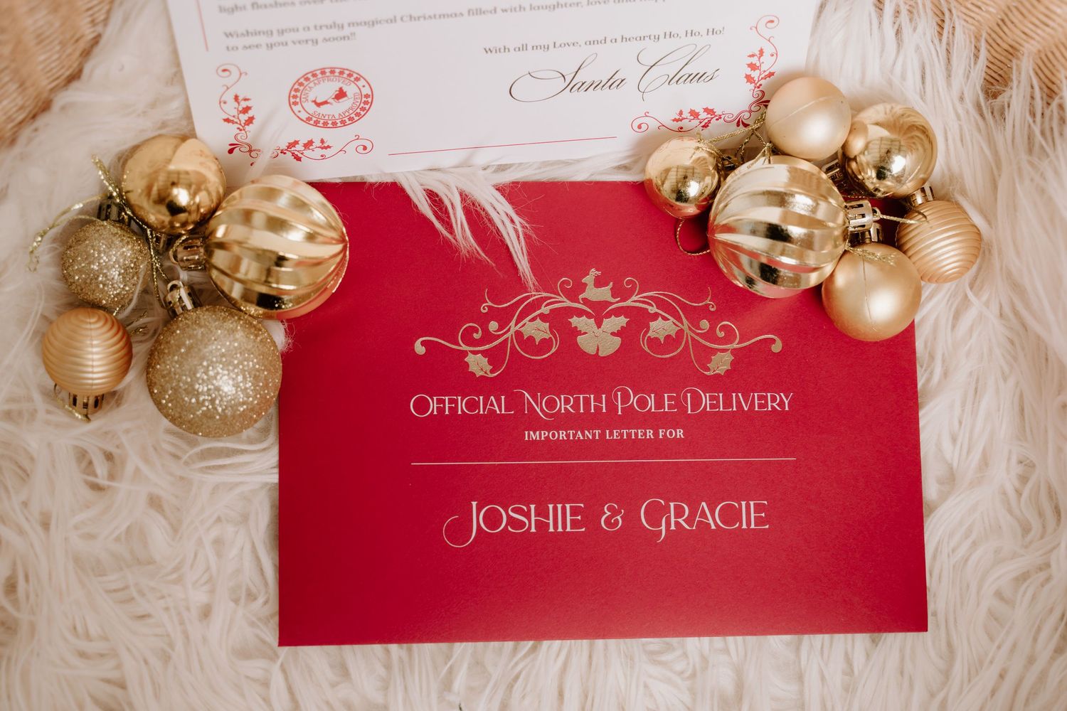 Red Official North Pole Delivery envelope addressed to Joshie & Gracie surrounded by gold Christmas ornaments and a Santa letter.