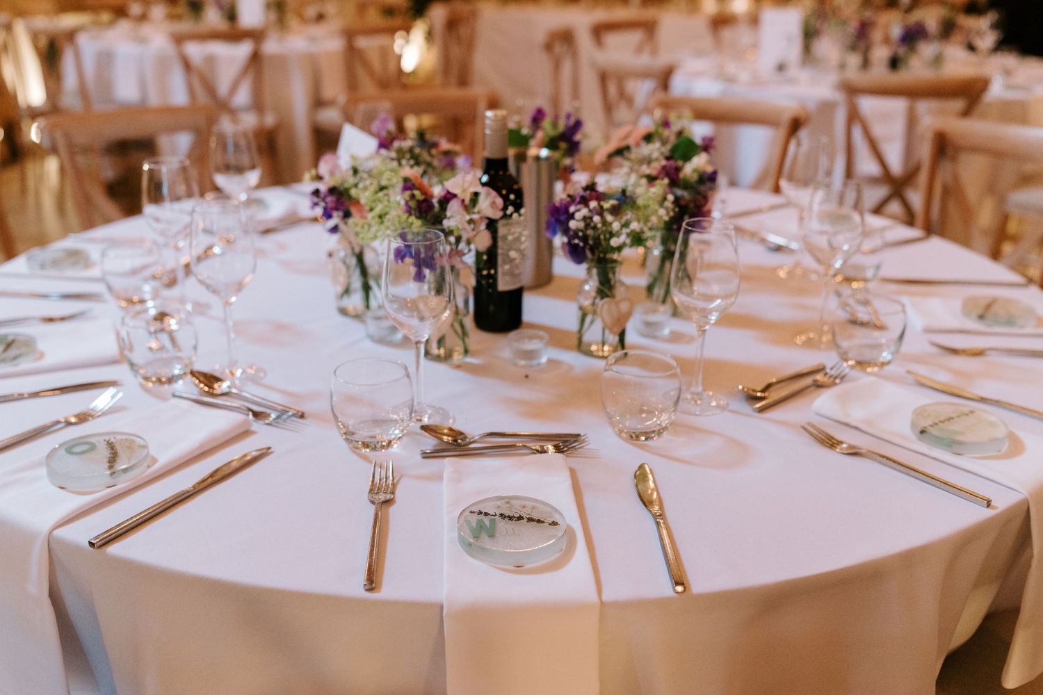 Elegant wedding reception table with white linen, gold cutlery, and colorful floral centerpieces.