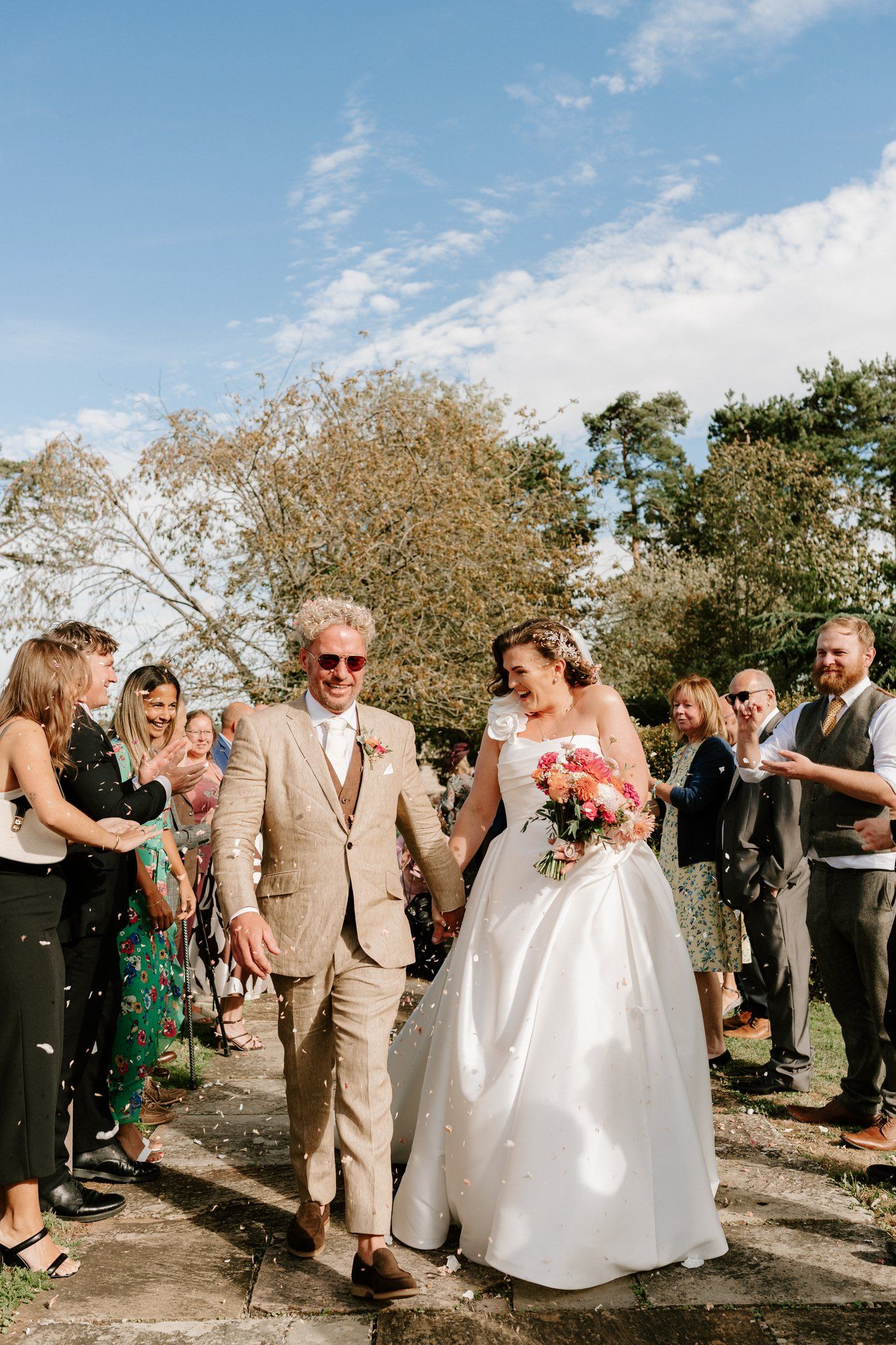 Bride and groom walking through a long confetti line at Brinsop Court, Herefordshire