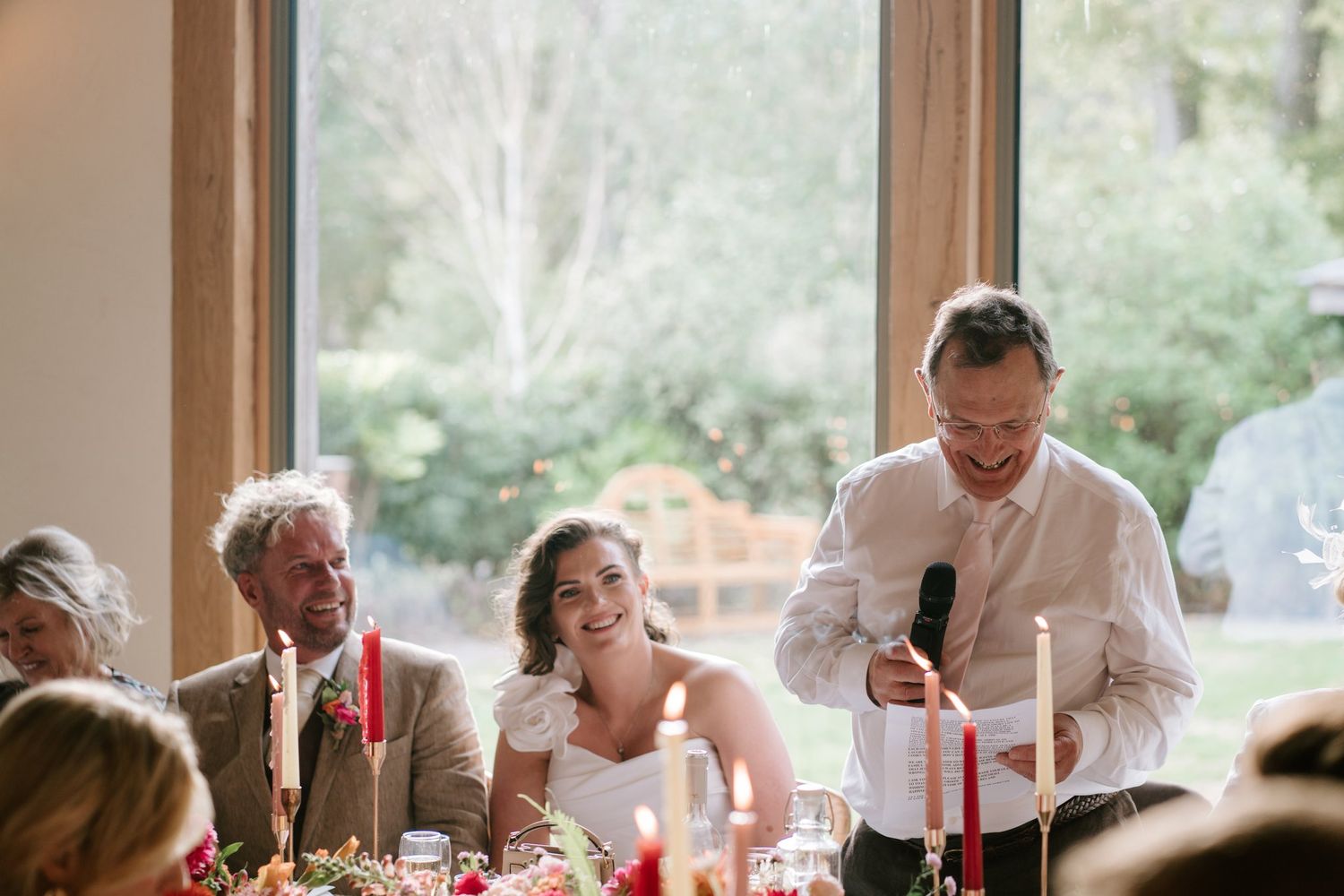 Bride and groom laughing during the speeches in the Knot Barn at Brinsop Court
