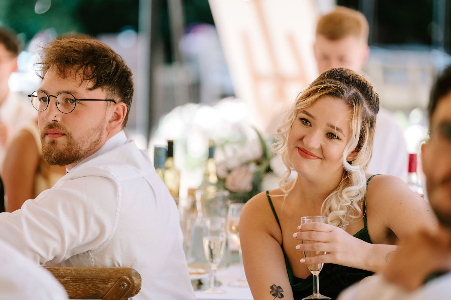Wedding guests smiling and enjoying drinks at elegantly decorated reception table.