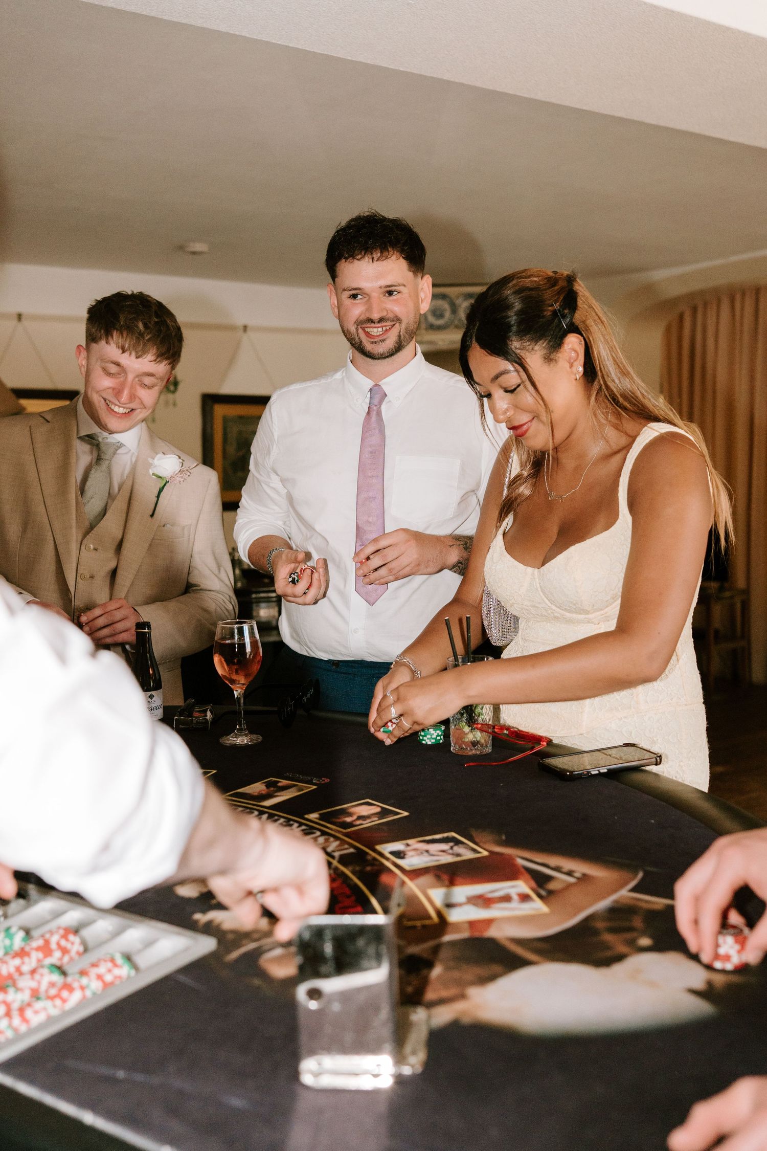 Bride and groom laughing at casino table with wedding guests during wedding reception party.