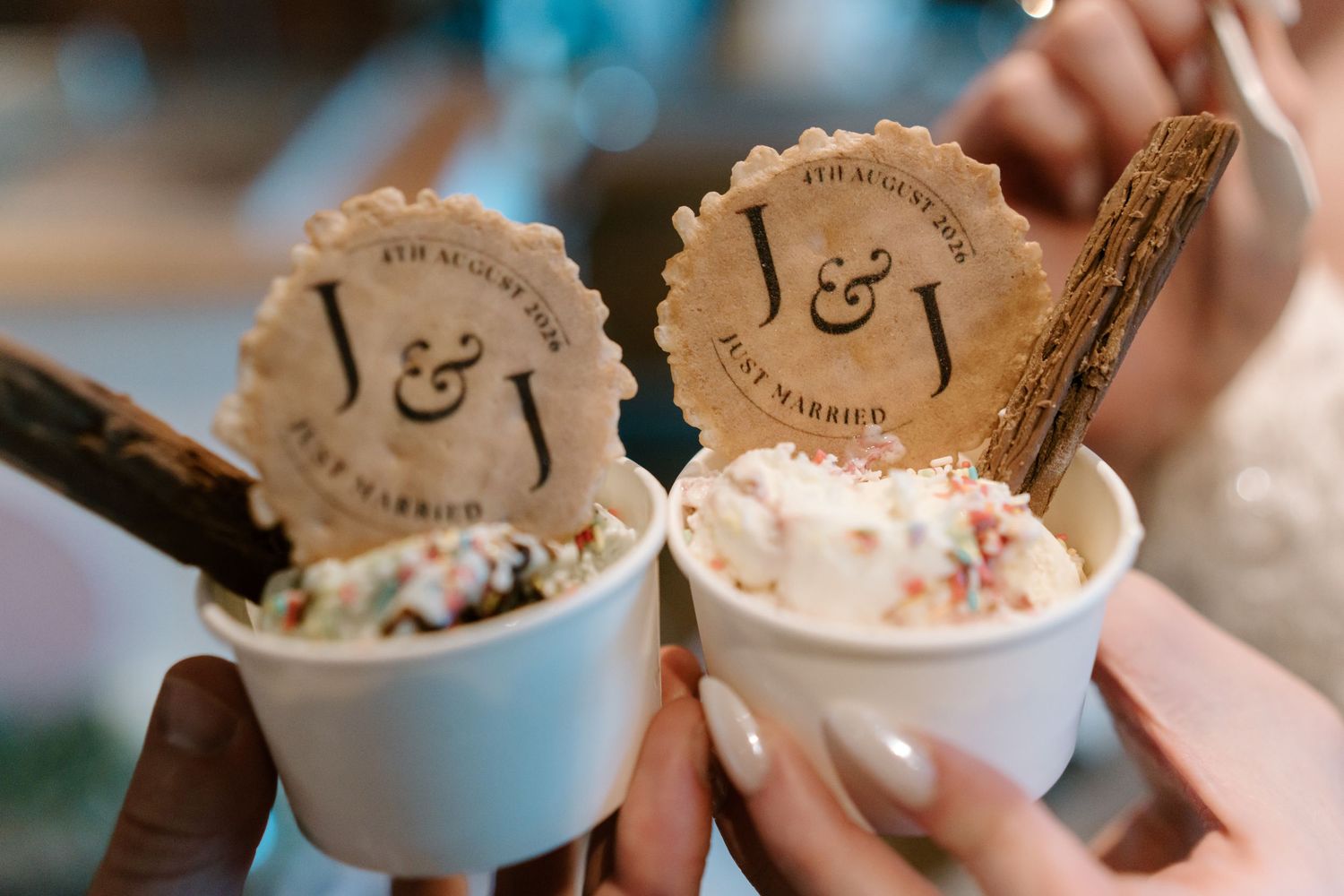 Two cups of ice cream topped with sprinkles and custom J&J Just Married wedding cookie decorations.