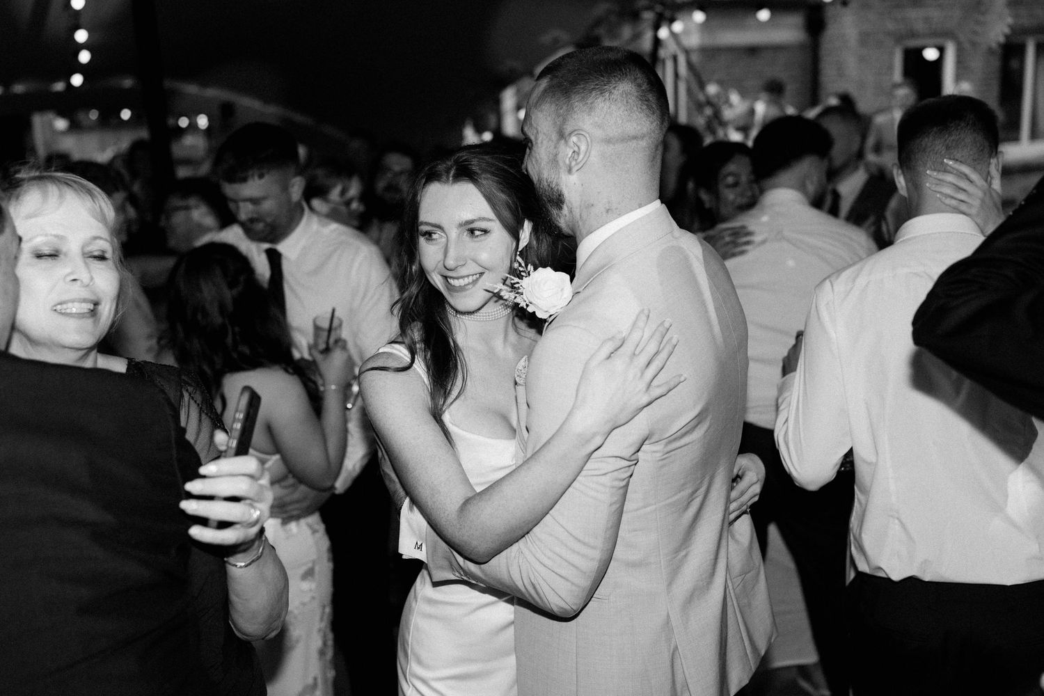 Bride and groom sharing romantic slow dance together at evening wedding reception in black and white.