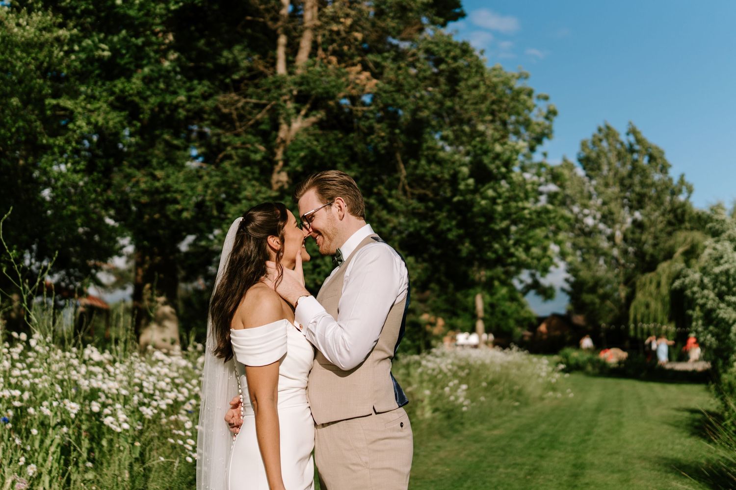 Bride and groom share a romantic moment surrounded by wildflowers and lush greenery on wedding day.