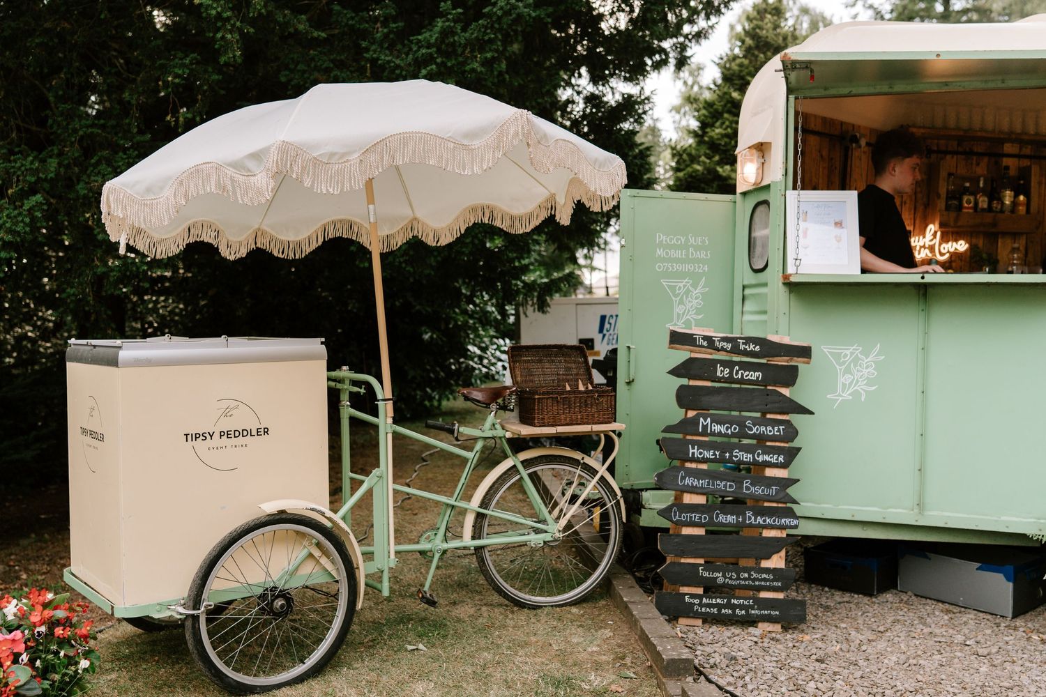Vintage mint green ice cream cart and caravan with menu signs at outdoor wedding.