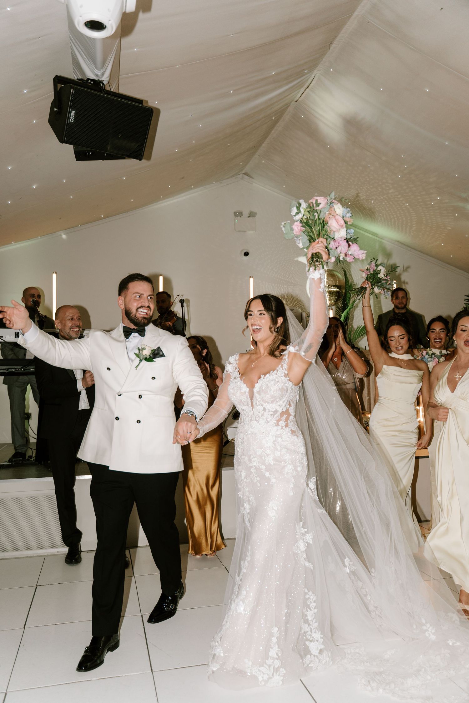 Bride and groom make grand entrance raising hands at elegant wedding reception venue.