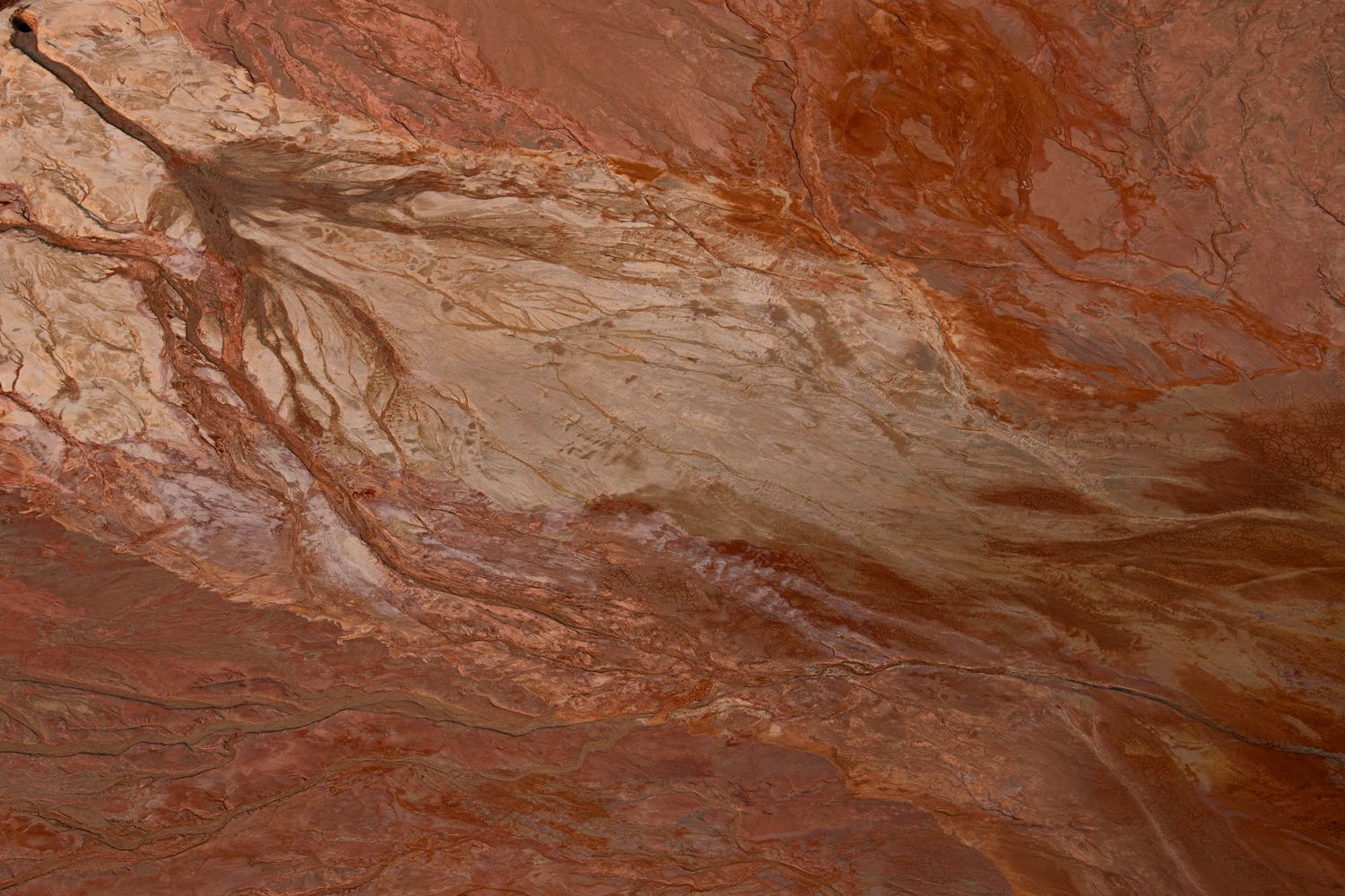 Close-up of red and orange swirling mineral patterns in desert sandstone rock surface texture.