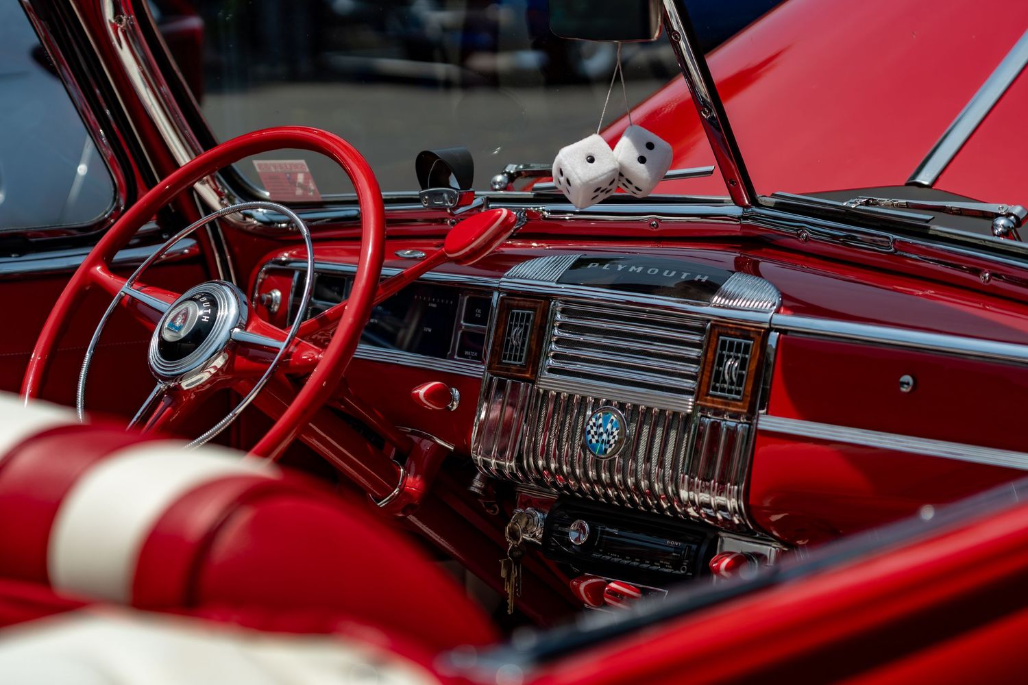 Classic red Mercury car interior with vintage dashboard, steering wheel, and fuzzy dice.