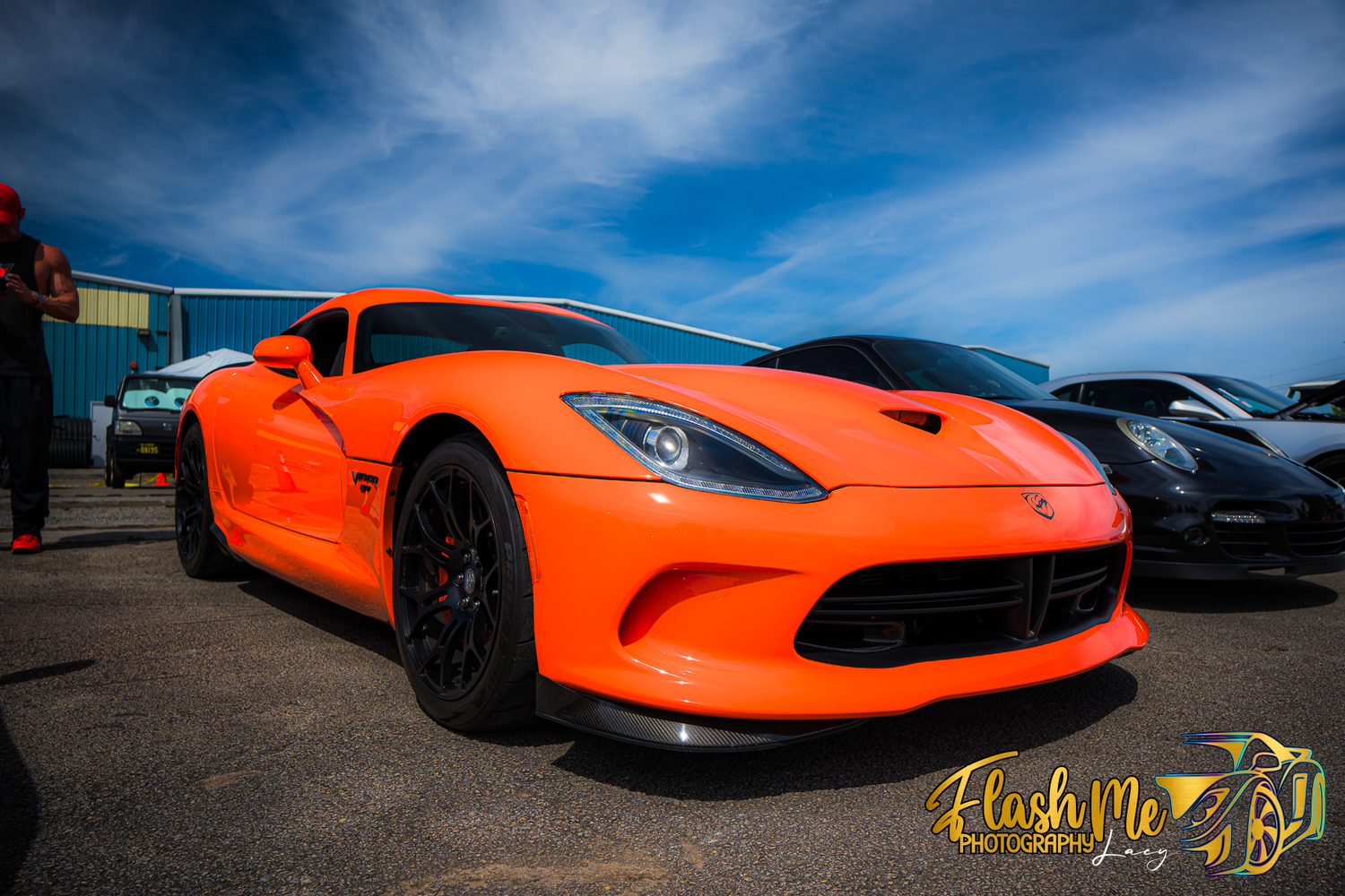 Bright orange Dodge Viper SRT supercar displayed at an outdoor car show under a blue sky.