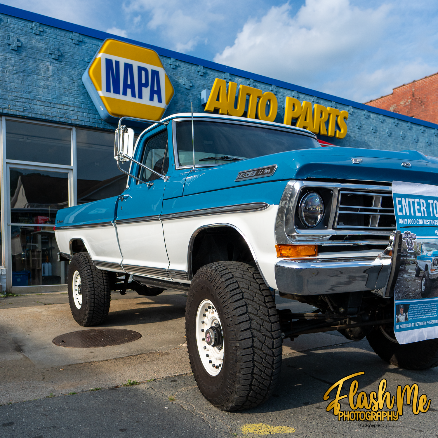 Classic lifted blue and white Ford F-250 truck parked in front of a NAPA Auto Parts store.