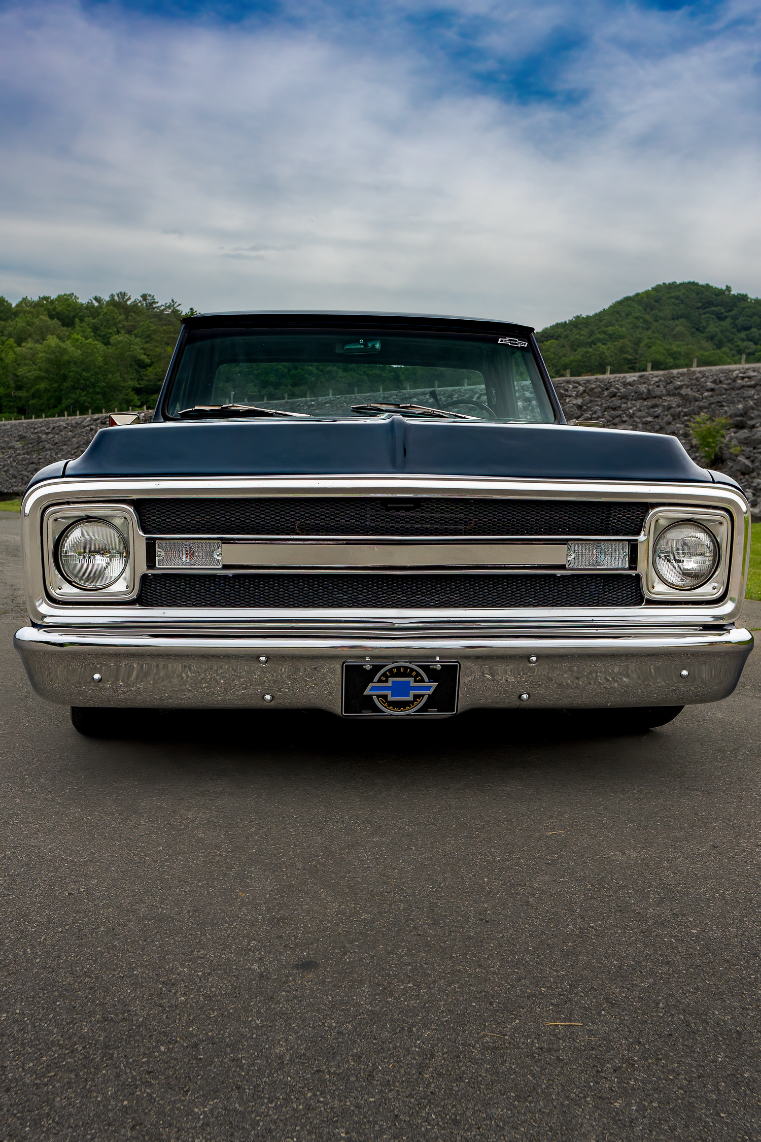 Front view of a restored black classic Chevrolet C10 pickup truck on an open road.