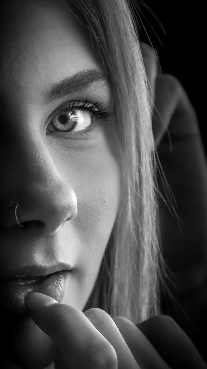 Close-up black and white portrait of a woman with striking eyes and a nose ring.